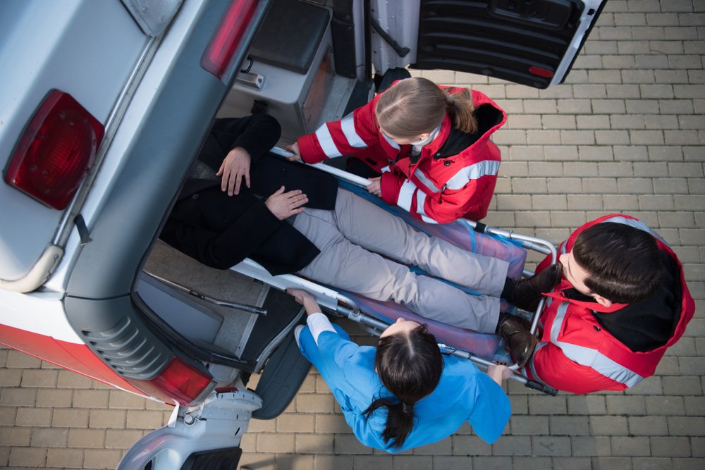 Une équipe ambulancière transporte un homme sur la civière d’ambulance dans la voiture. | Shutterstock