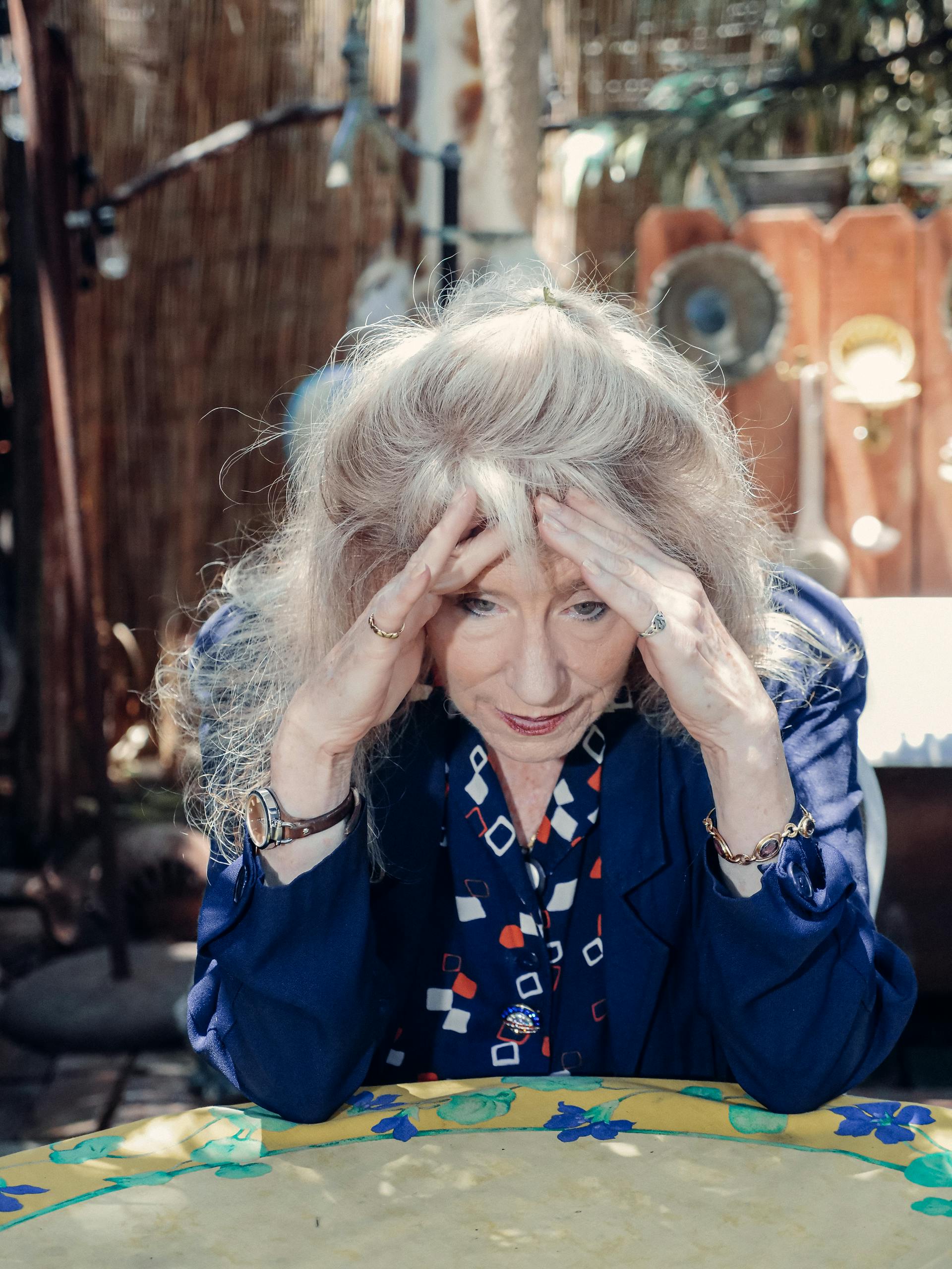 An elderly woman resting her head in her hands | Source: Pexels