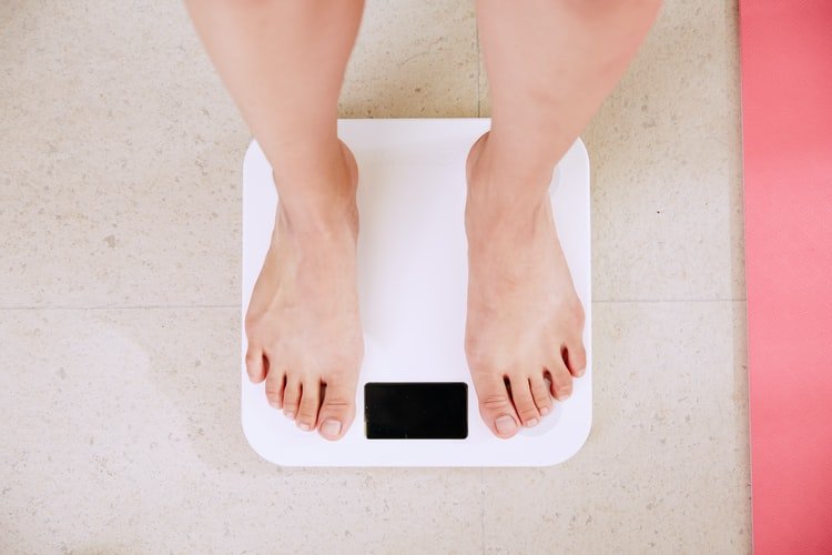 A man checking his weight on the scale. | Photo: Unsplash.