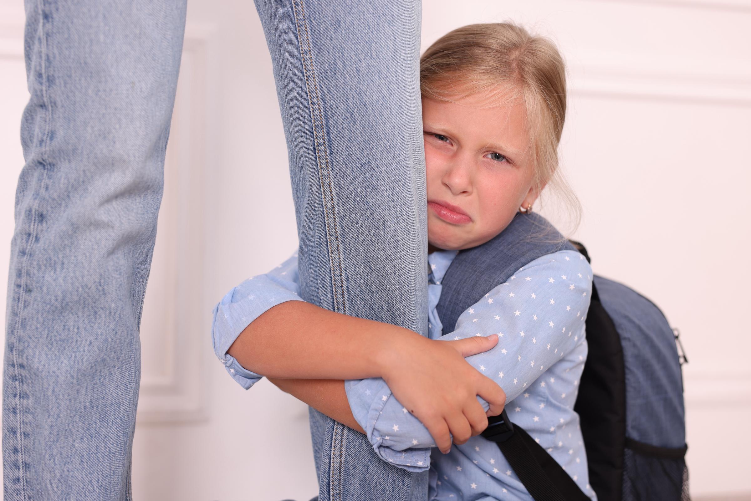 Little girl crying while clenching on to with an adult's leg | Source: Shutterstock