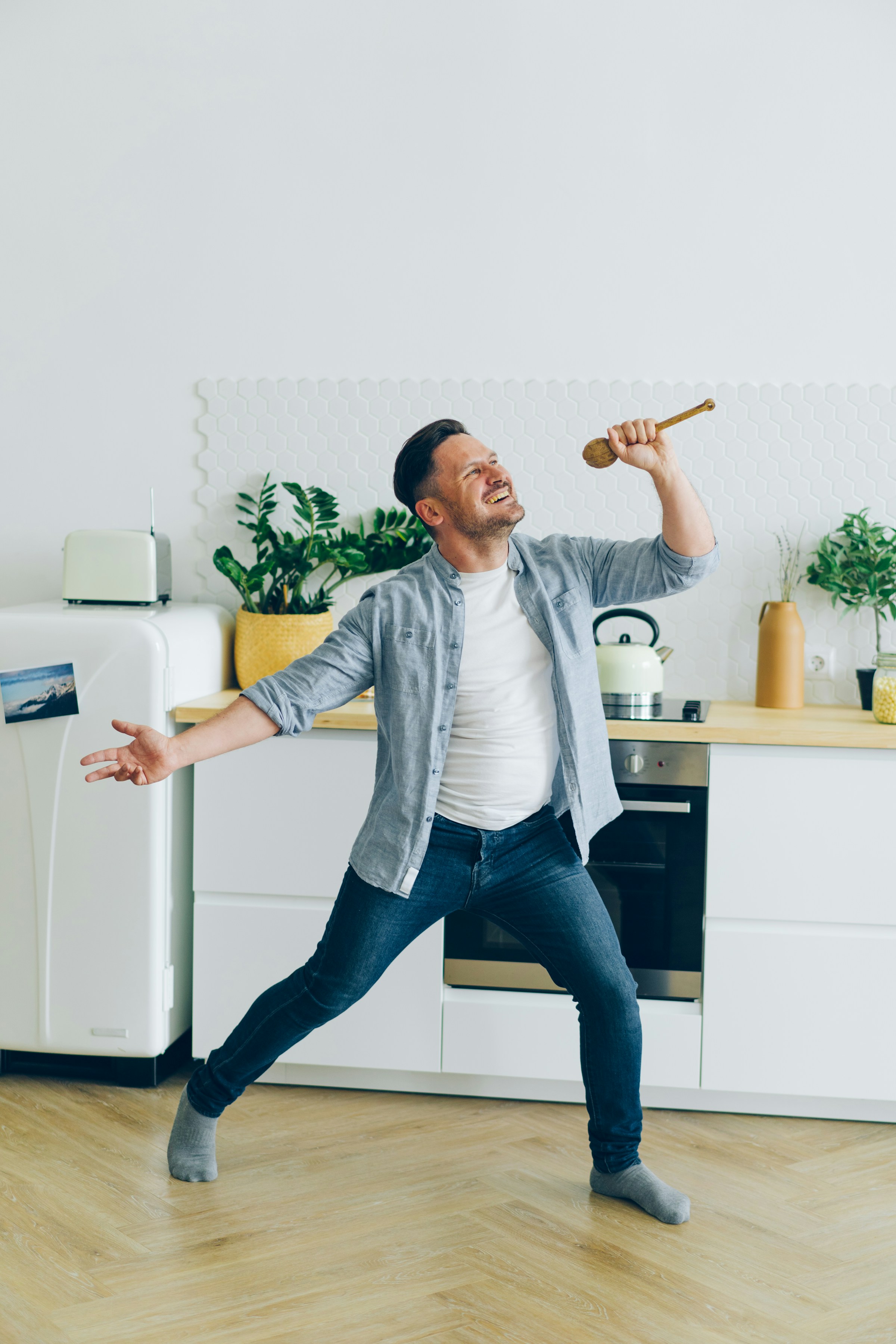 A man having fun in the kitchen holding a wooden spoon | Source: Unsplash