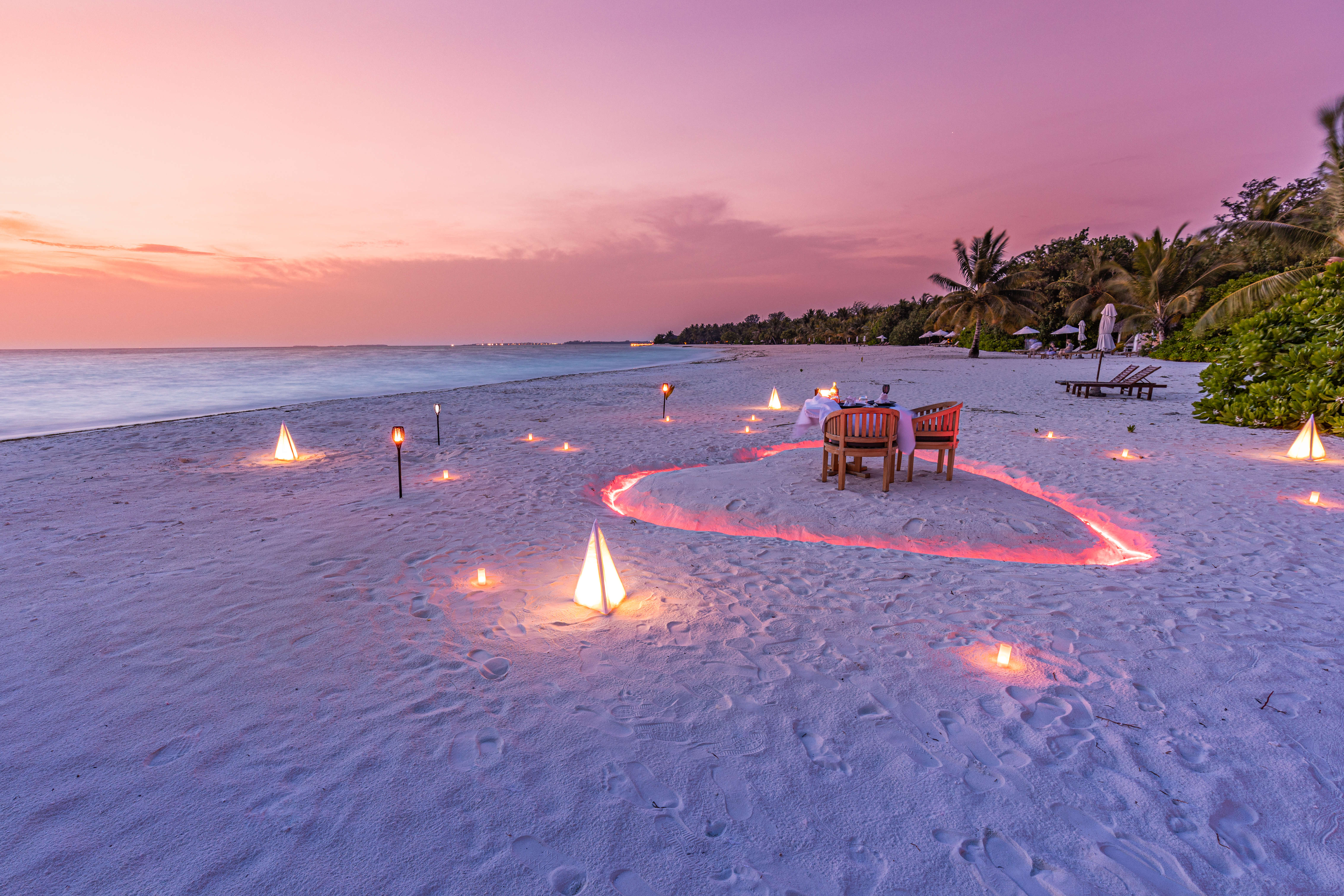 Luxury honeymoon destination, romantic dinner with candles heart on the calm sand beach landscape. Luxury wedding anniversary dinner | Source: Getty Images