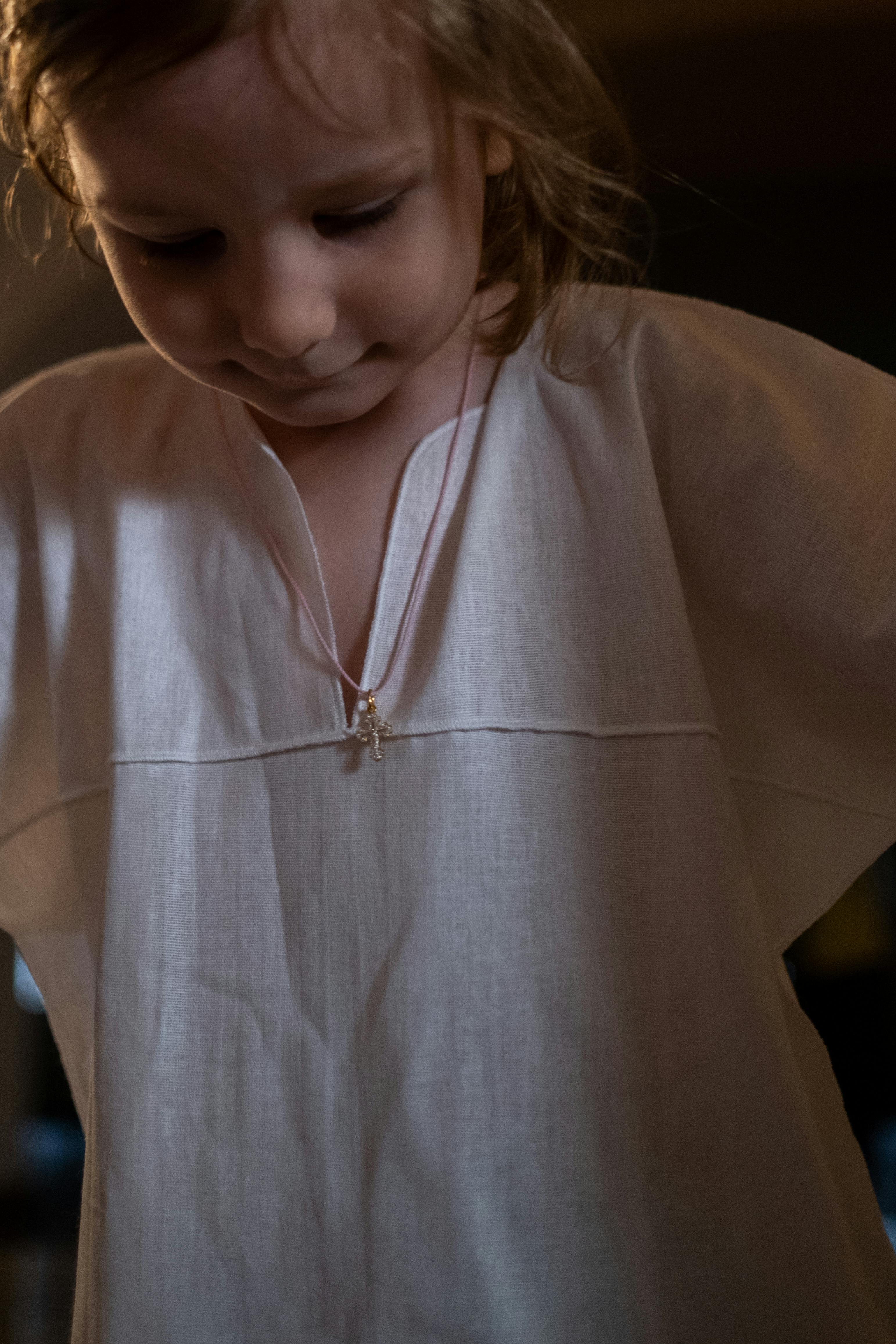 A little girl in a white dress looking down | Source: Pexels