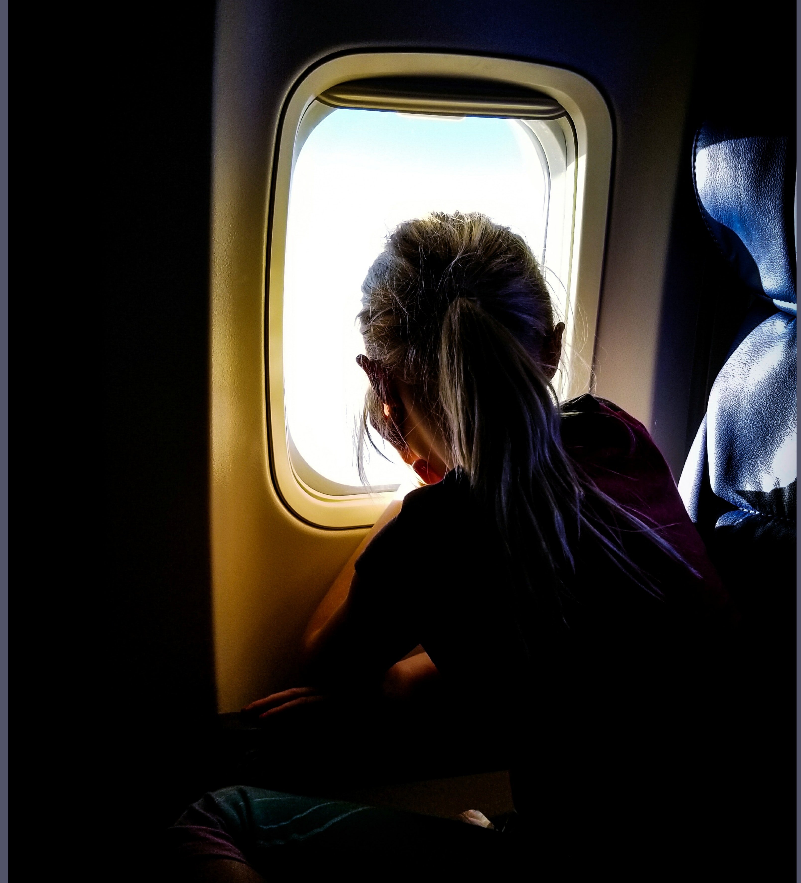 Woman staring outside a plane window | Photo: Unsplash