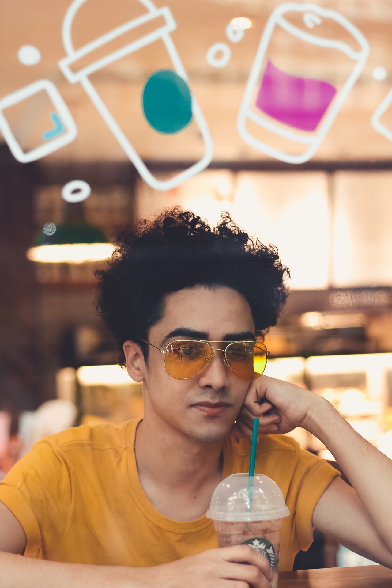 Un joven sentado en una cafetería bebiendo un café. | Foto: Pexels