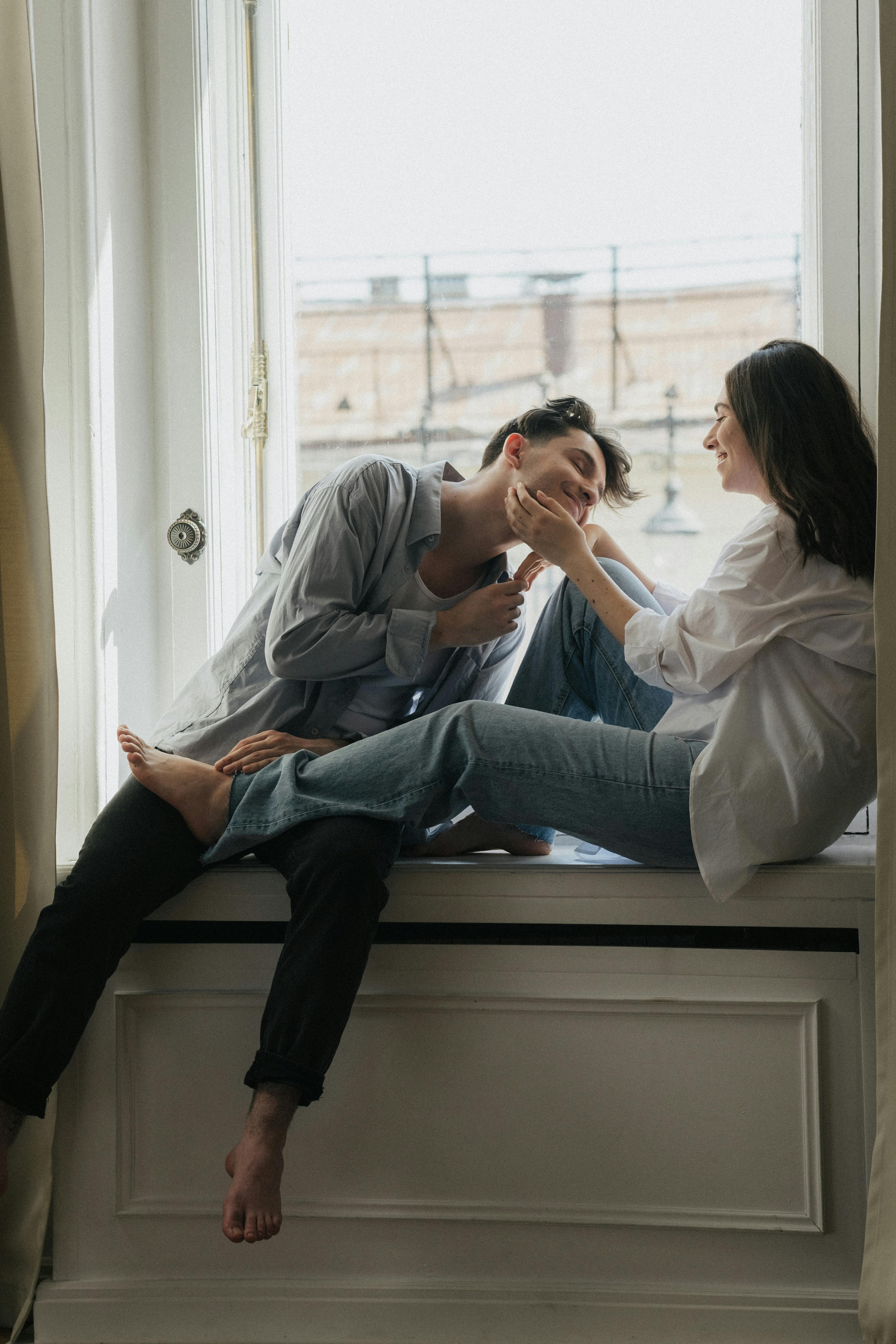 A happy couple hanging out on a windowsill | Source: Pexels
