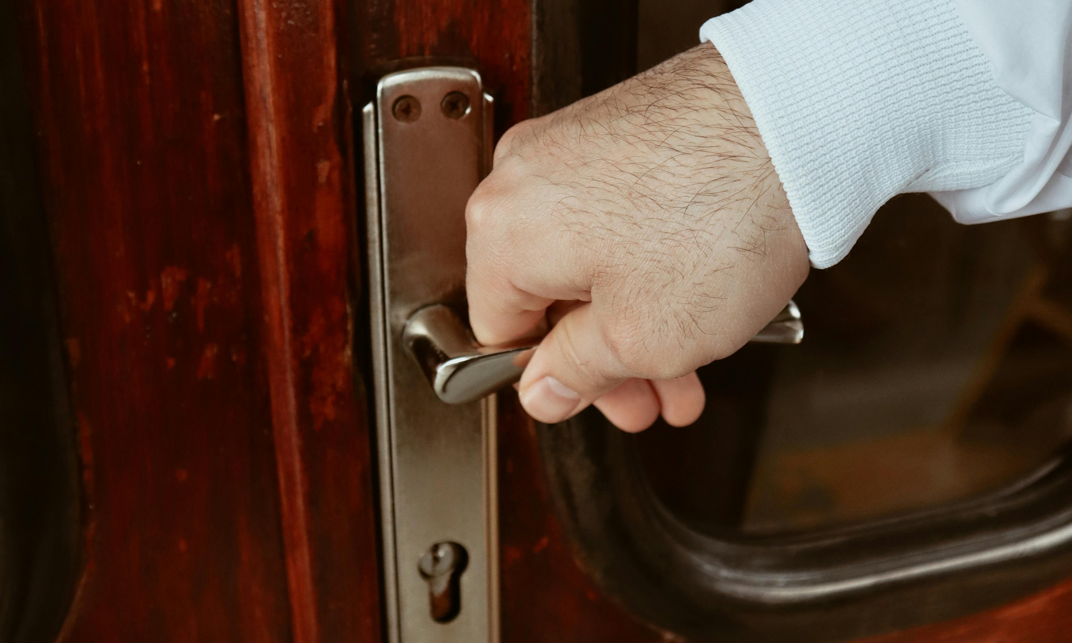 A close-up of a hand grasping a door handle | Source: Pexels