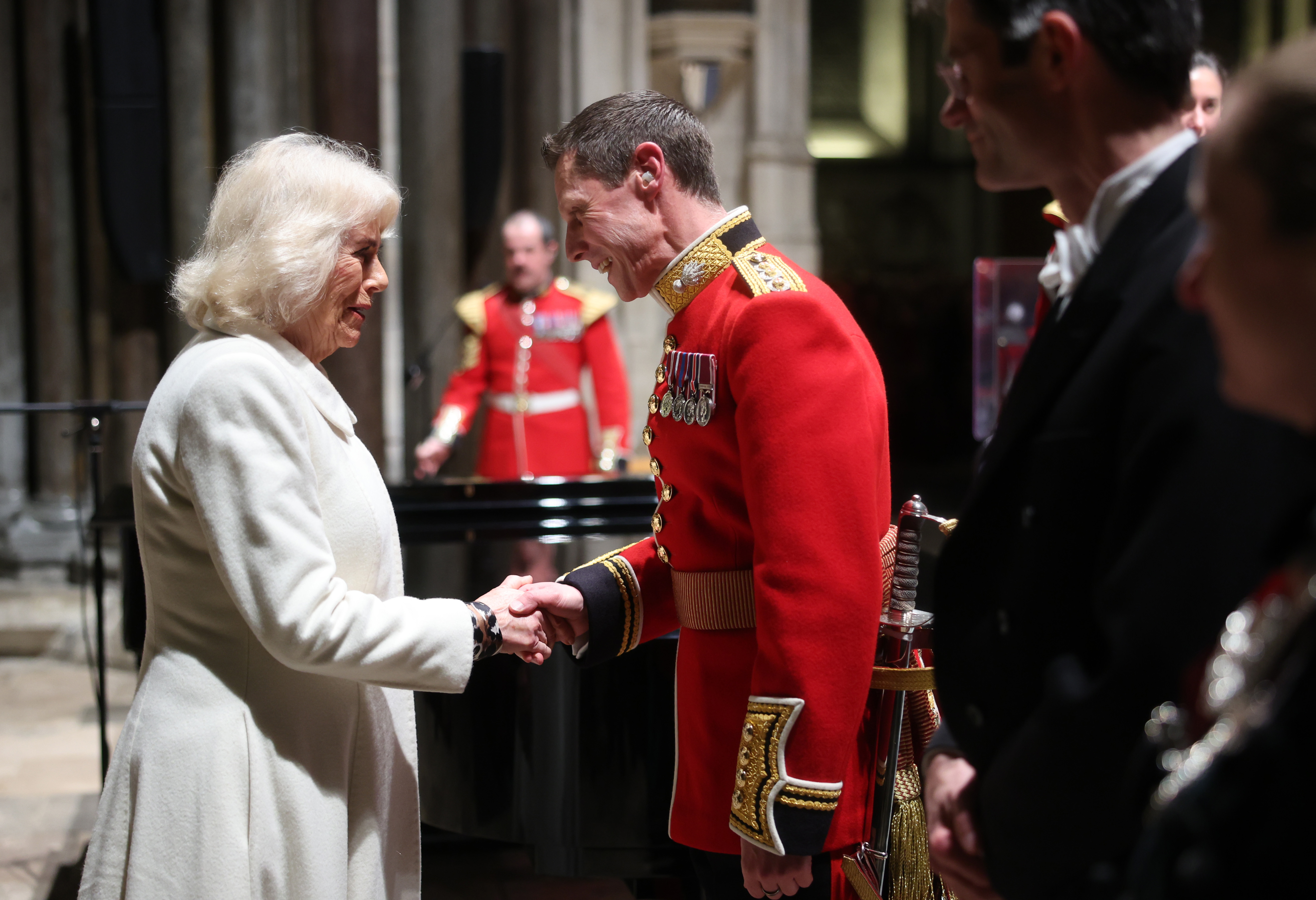 Queen Camilla shakes hands with Captain Robert Smith Director of Music for the Grenadier Guards Band during a musical evening at Salisbury Cathedral on February 8, 2024 in Salisbury, England | Source: Getty Images