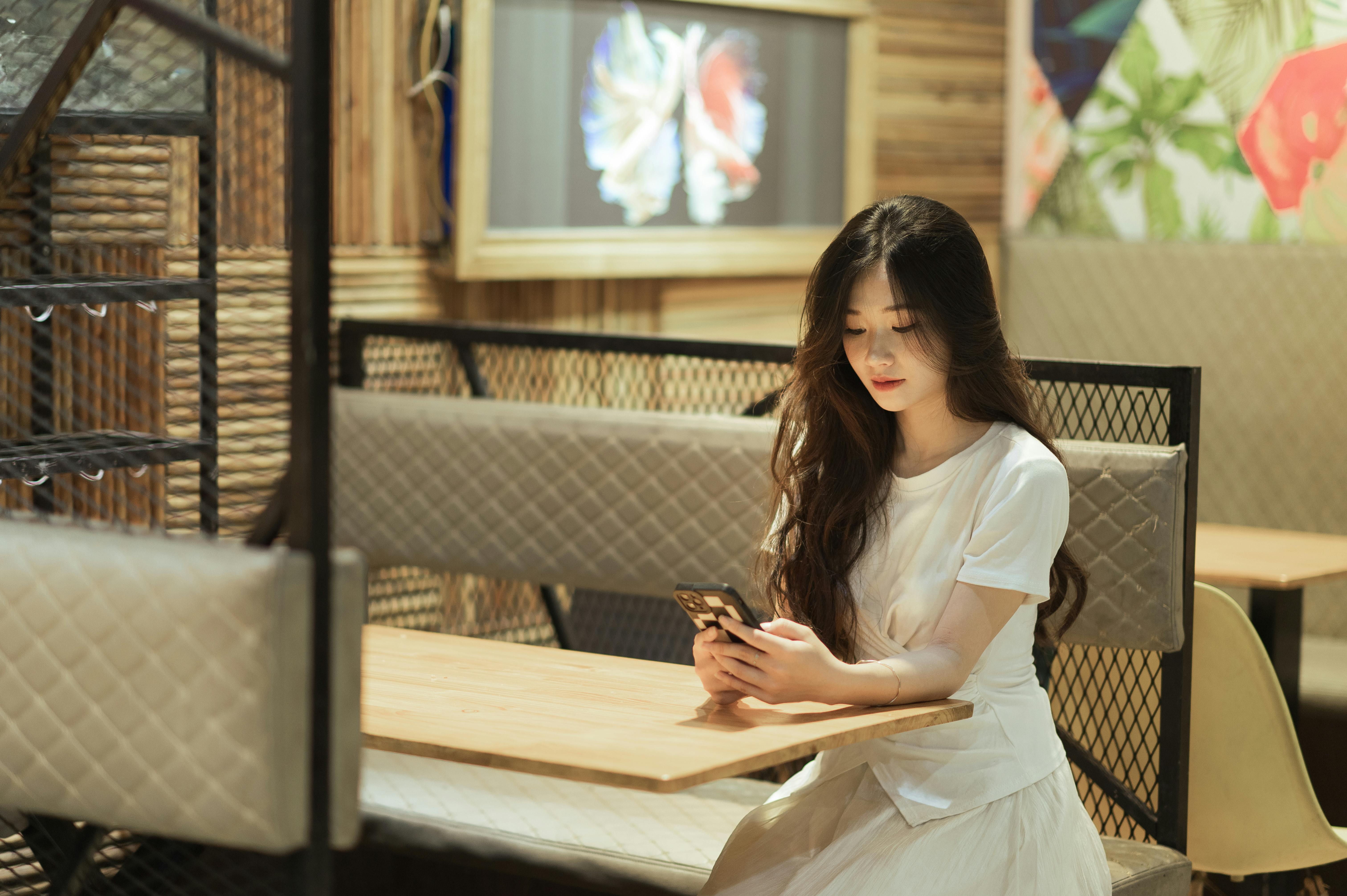 A woman checking her phone at a restaurant | Source: Pexels