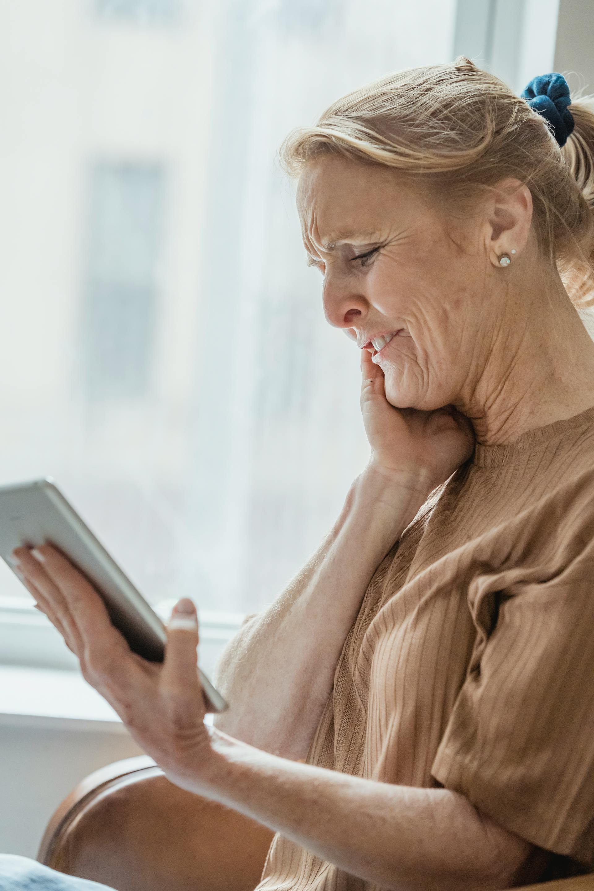 A smiling senior woman holding a tablet | Source: Pexels