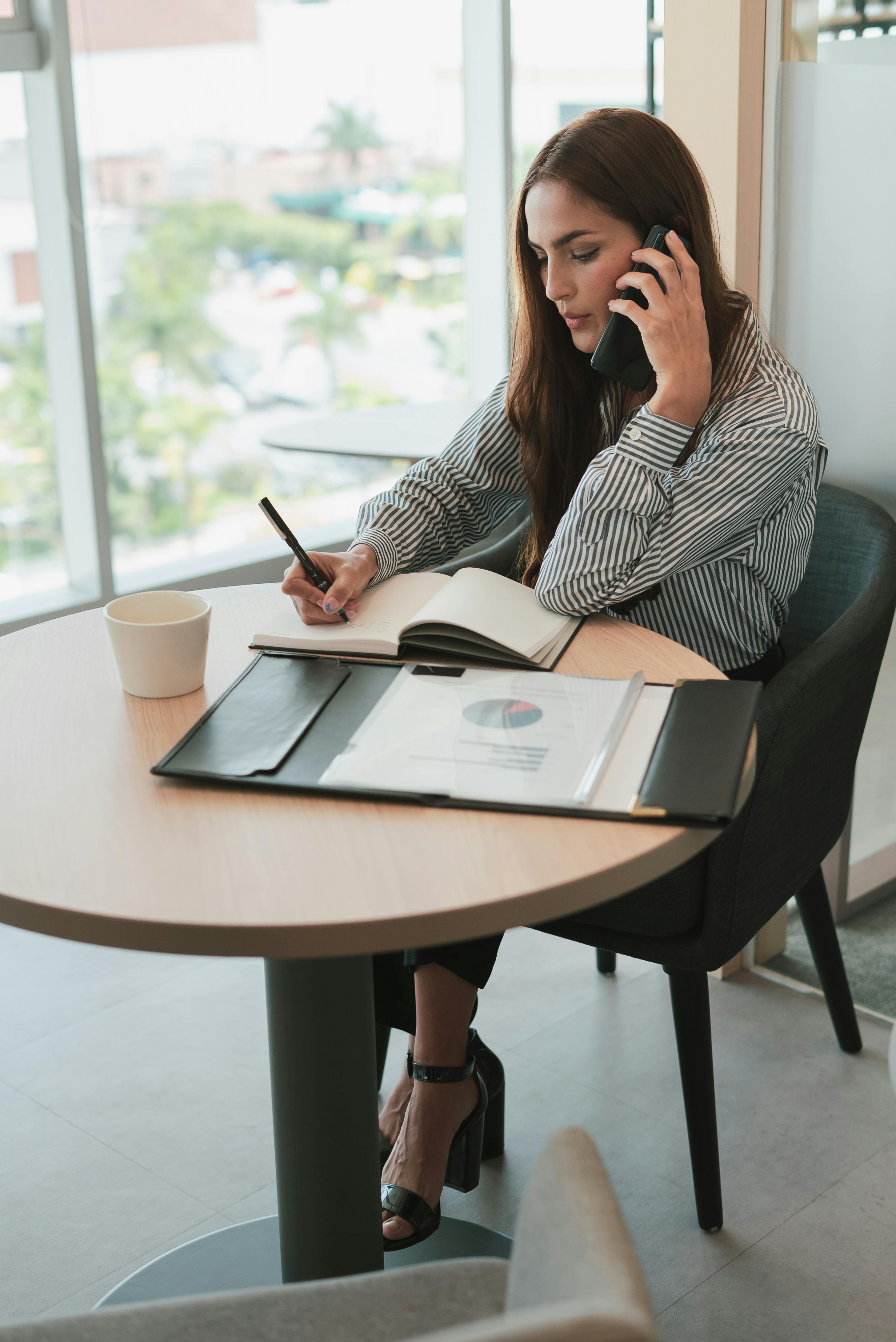 A young woman talking on her phone at her table | Source: Pexels