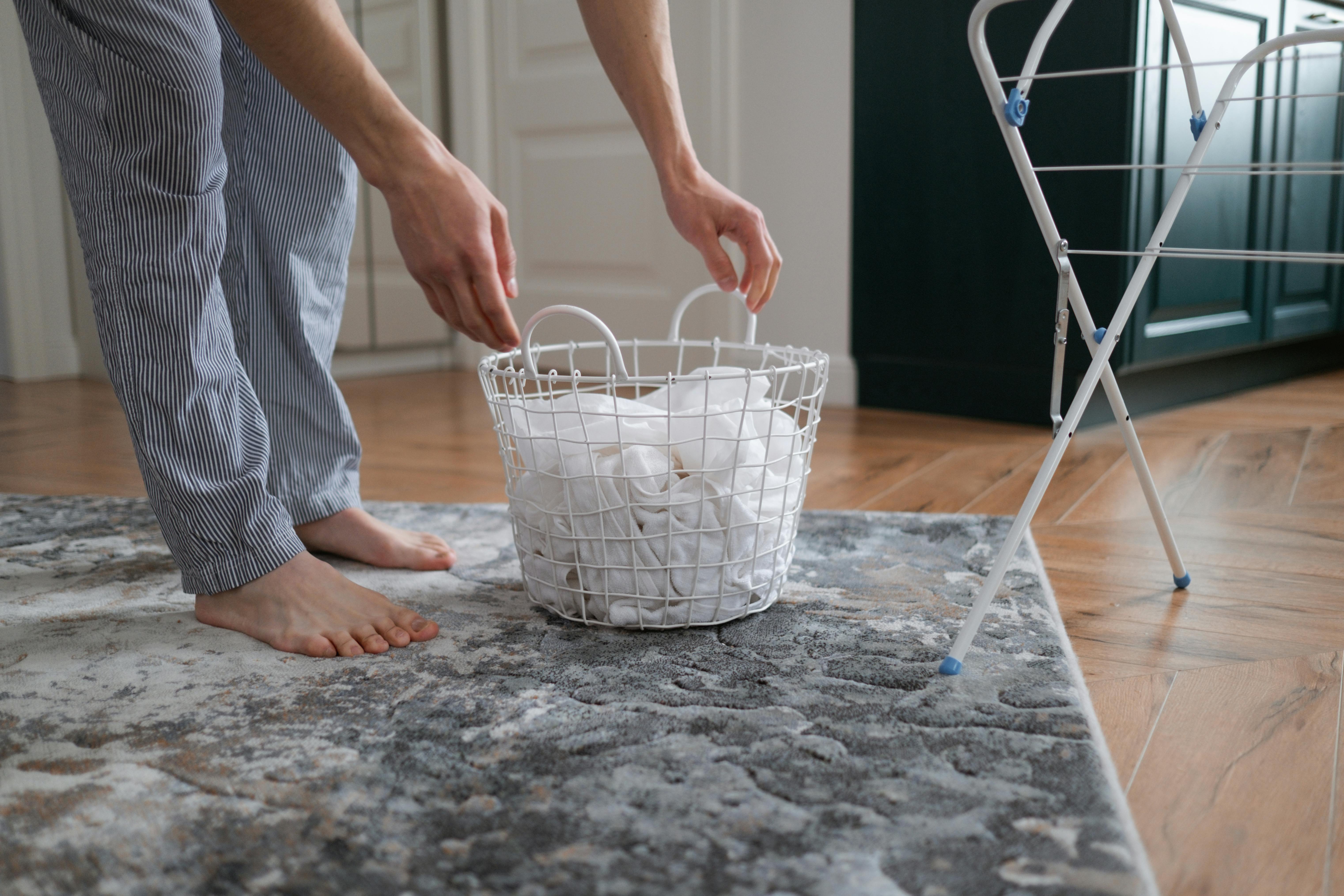 A person picking up their laundry hamper | Source: Pexels