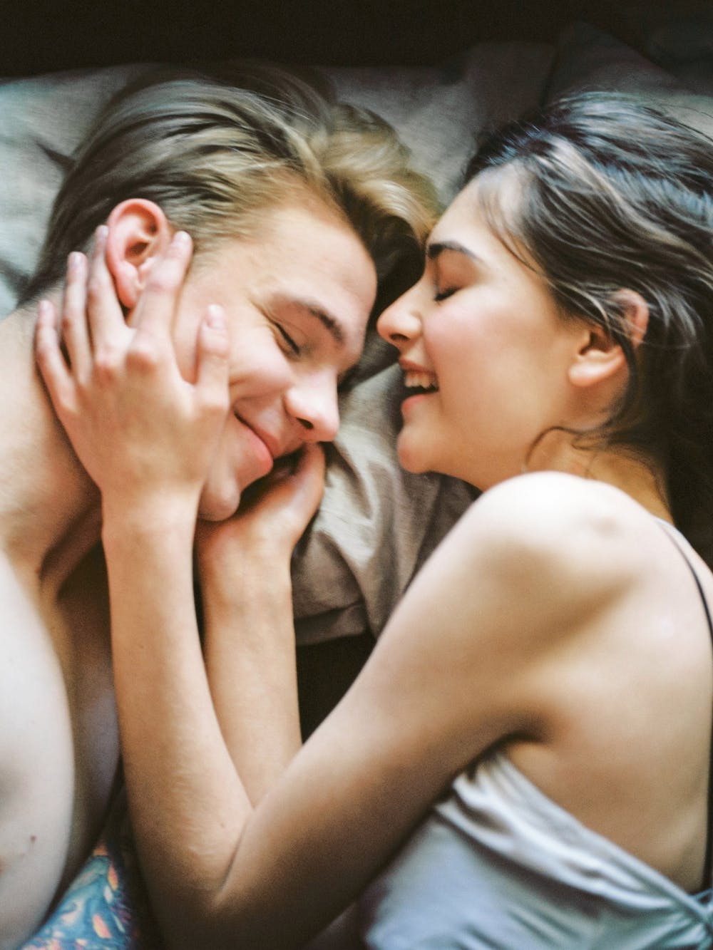 Pareja sonriendo en la cama. │Foto: Pexels
