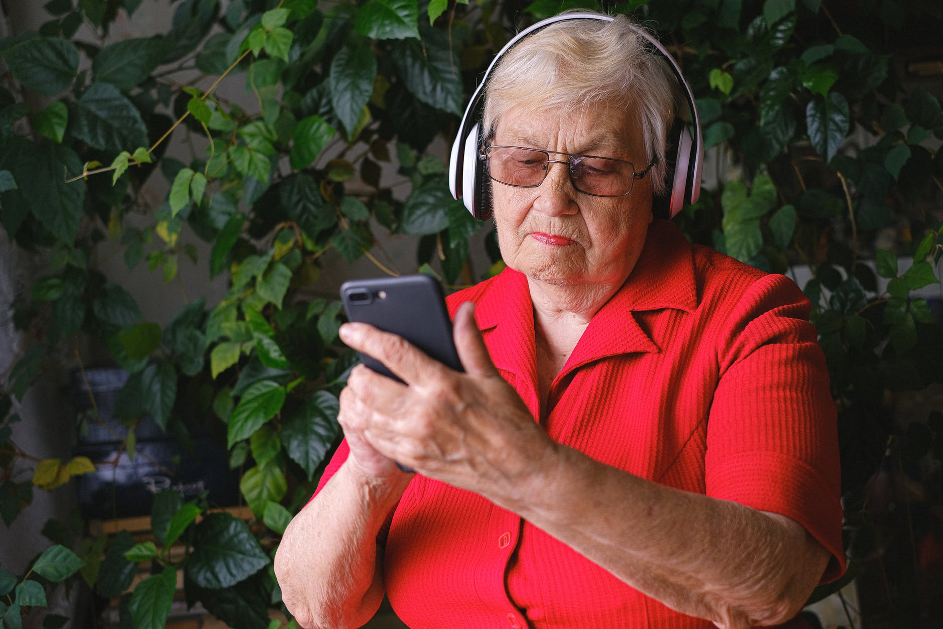 Mujer mayor con audífonos y celular. | Foto: Pexels