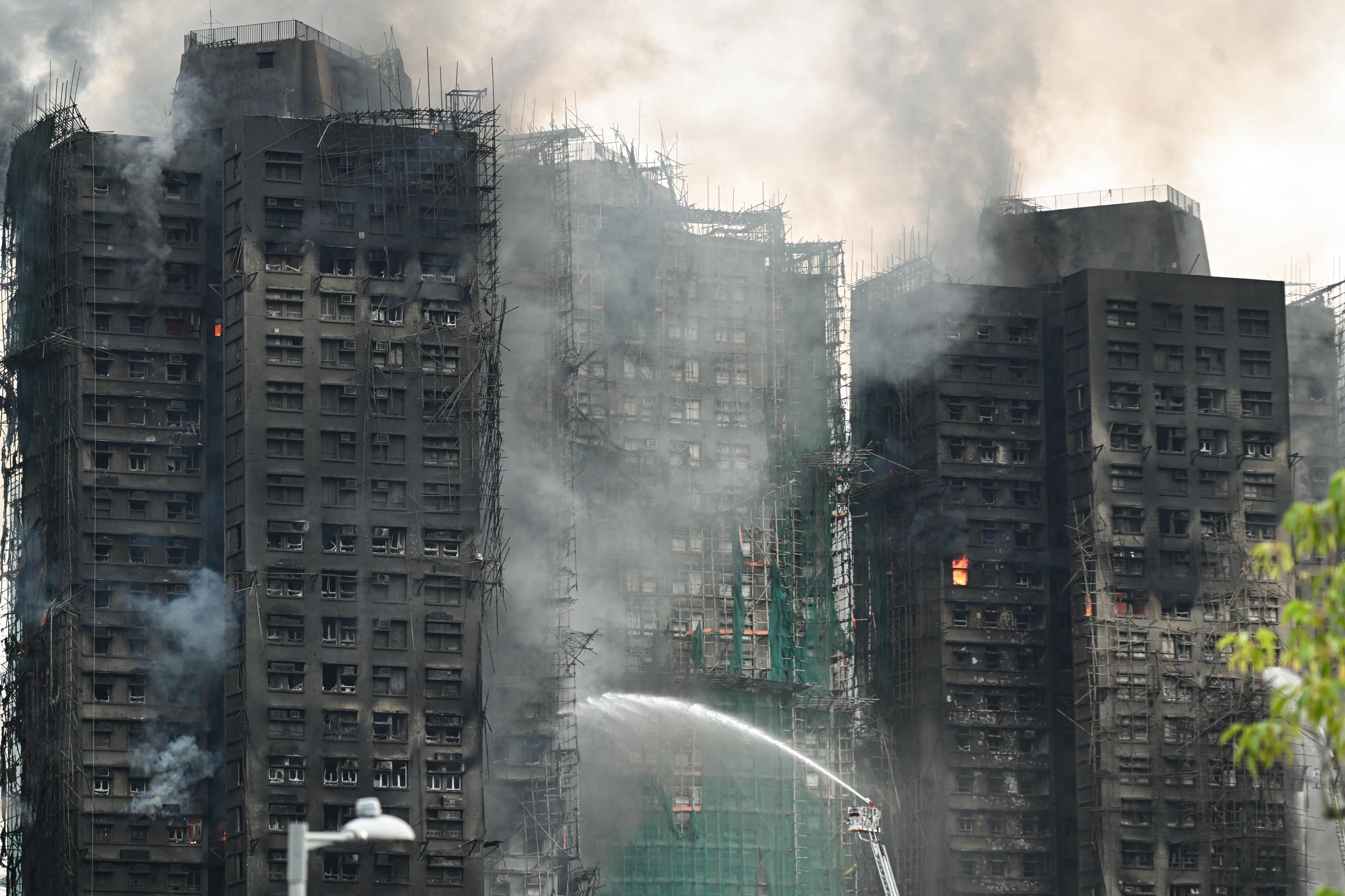 Firefighters spray water on flames as a major blaze burns through several apartment blocks at the Wang Fuk Court residential estate in Hong Kong's Tai Po district on November 27, 2025. | Source: Getty Images