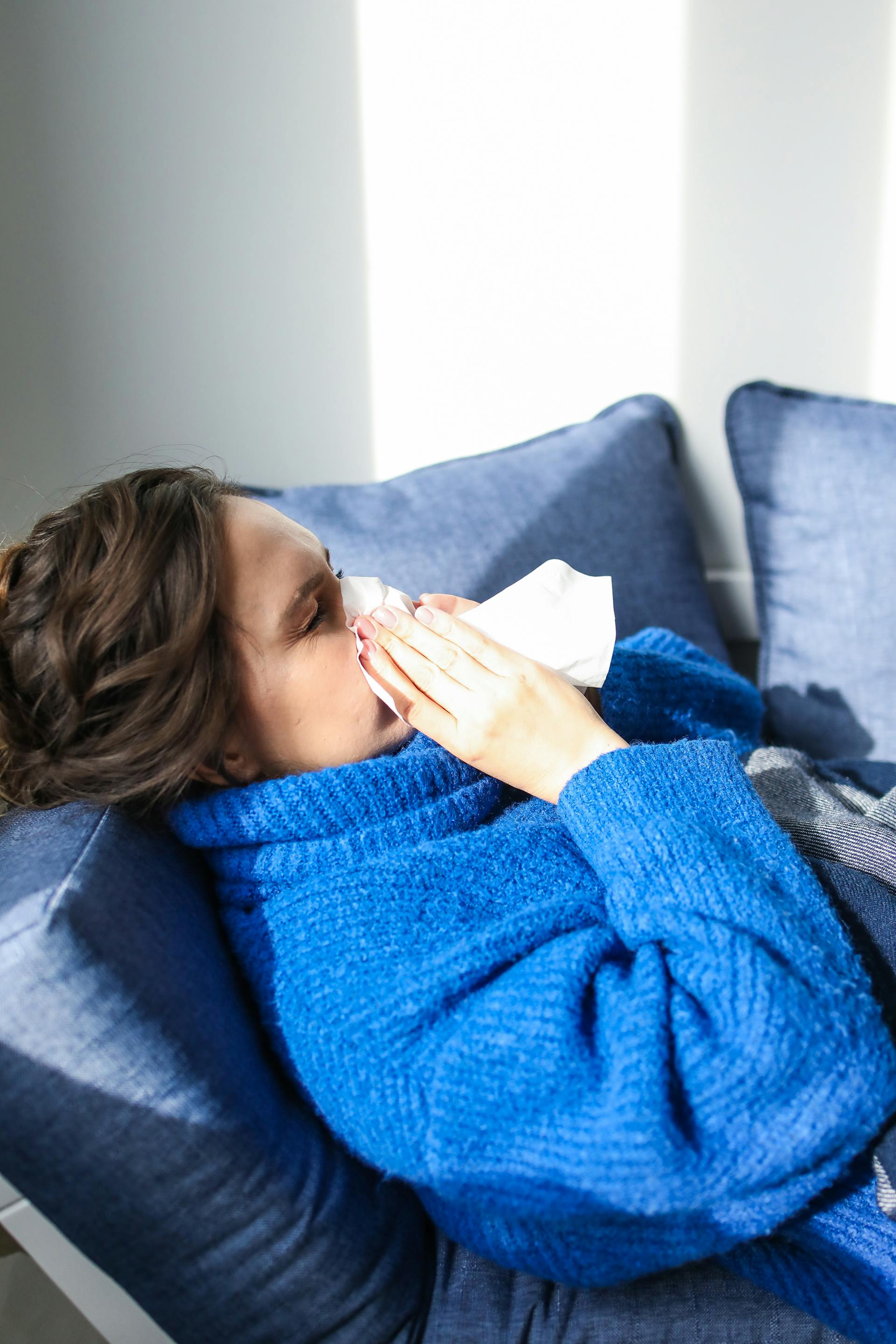 A sick woman lying on a couch | Source: Pexels