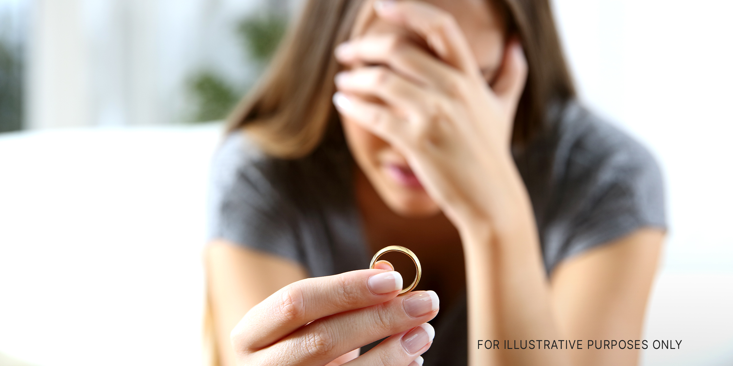 An upset woman holding an engagement ring | Source: Shutterstock