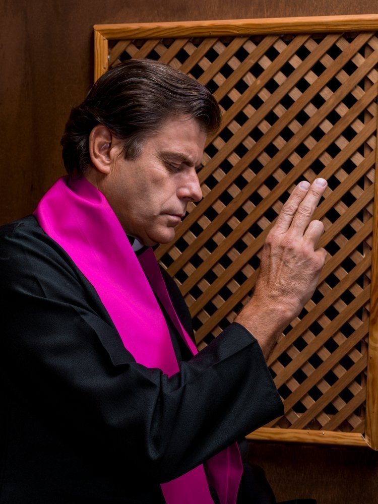 Priest in confession booth | Source: Shutterstock