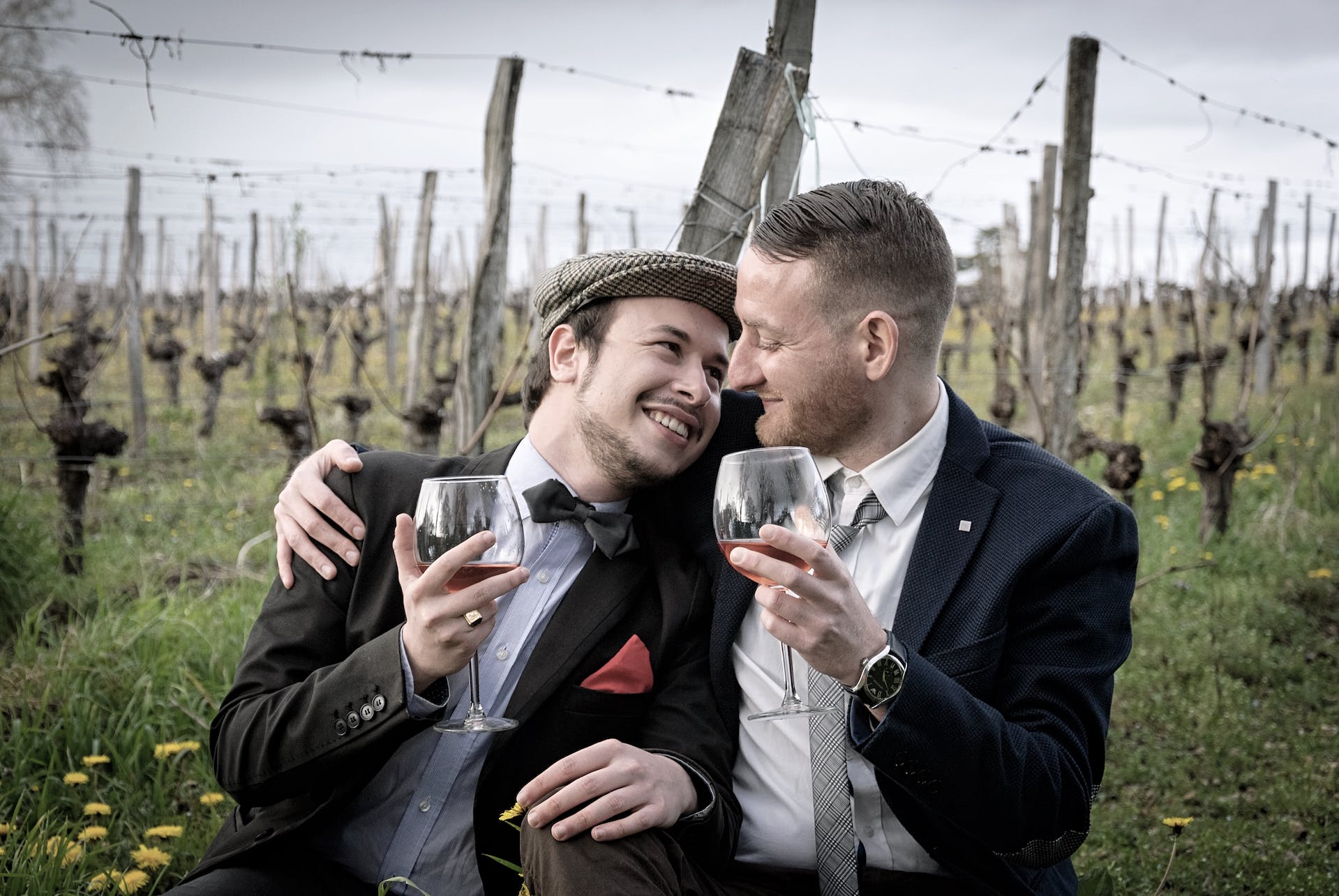 Two young men hug while drinking wine | Source: Pexels