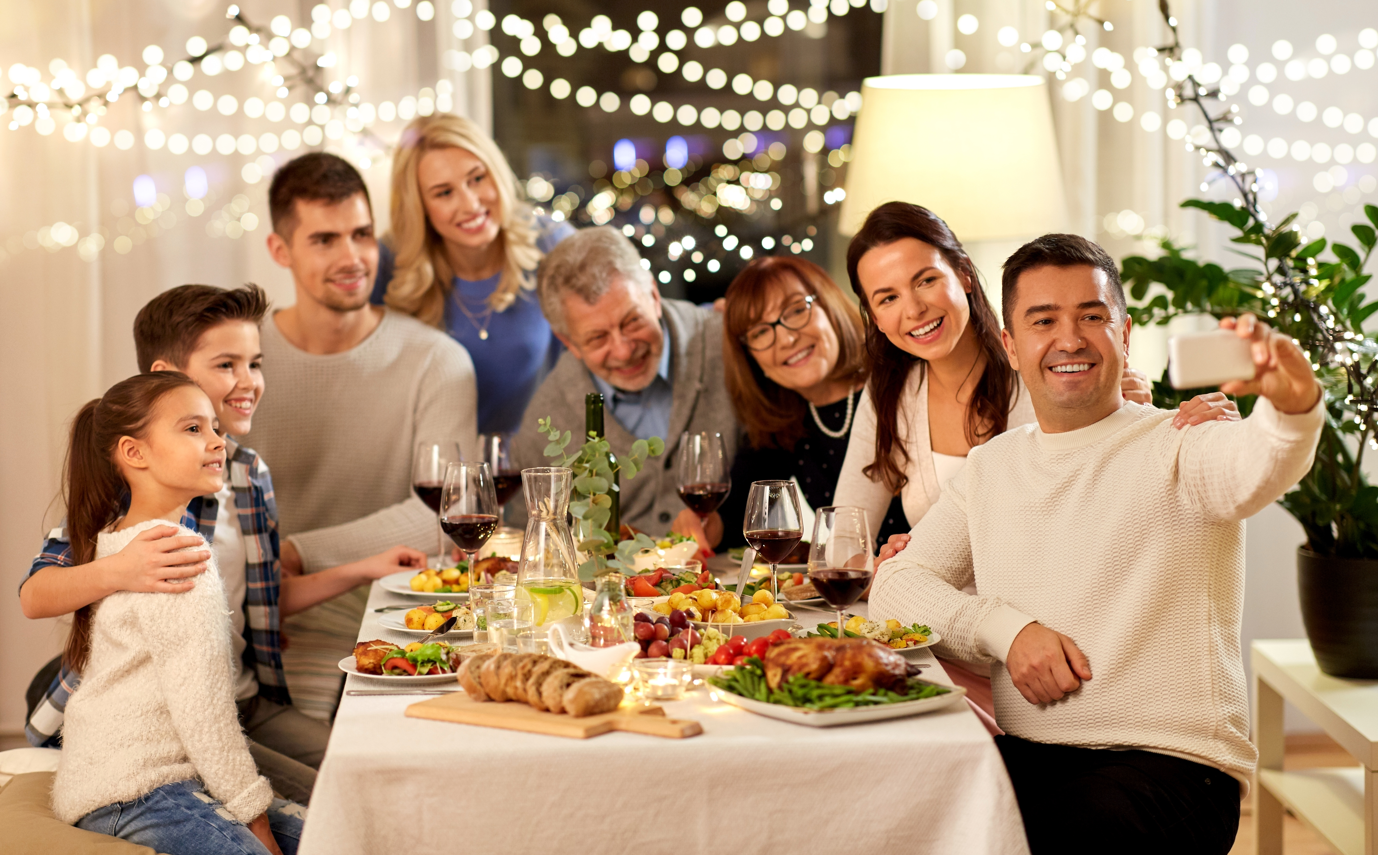 A man clicking a selfie at a family dinner | Source: Shutterstock