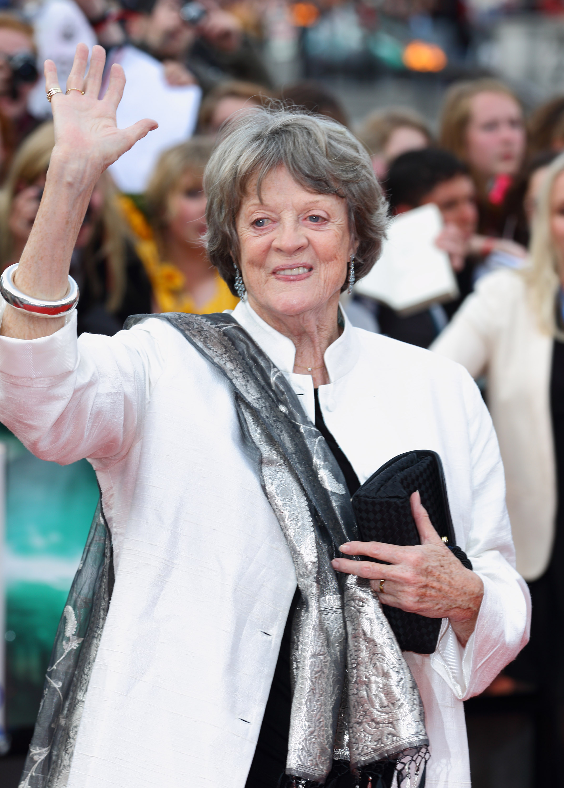 Maggie Smith attended the 2011 world premiere of "Harry Potter and the Deathly Hallows Part 2" in London with her signature grace. Wearing a white silk coat with a silver scarf and carrying a textured clutch, she greeted fans with a warm wave, embodying the poise of a seasoned screen legend.
