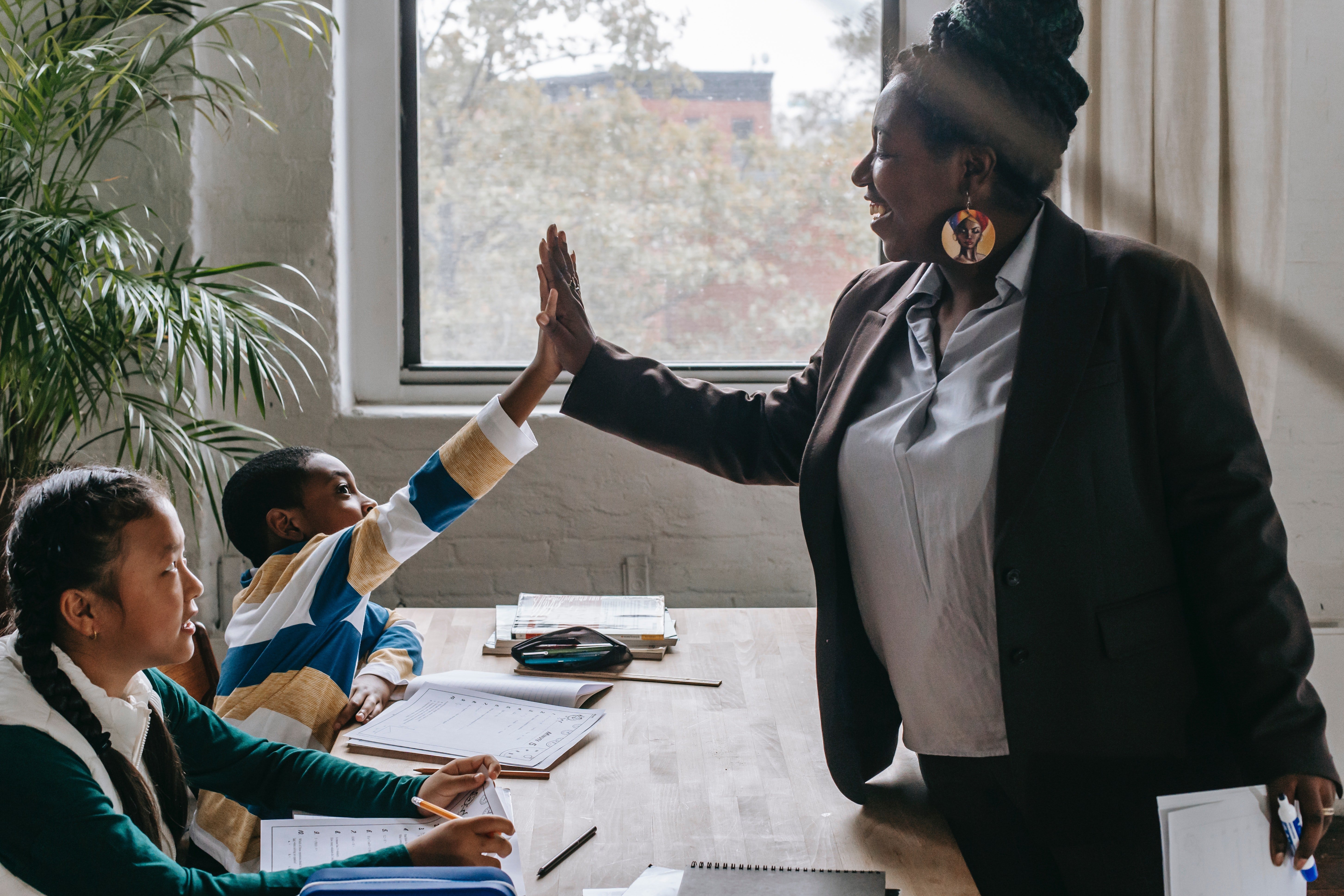 Pictured - A cheerful teacher giving a high five to one of her students in class | Source: Pexels 