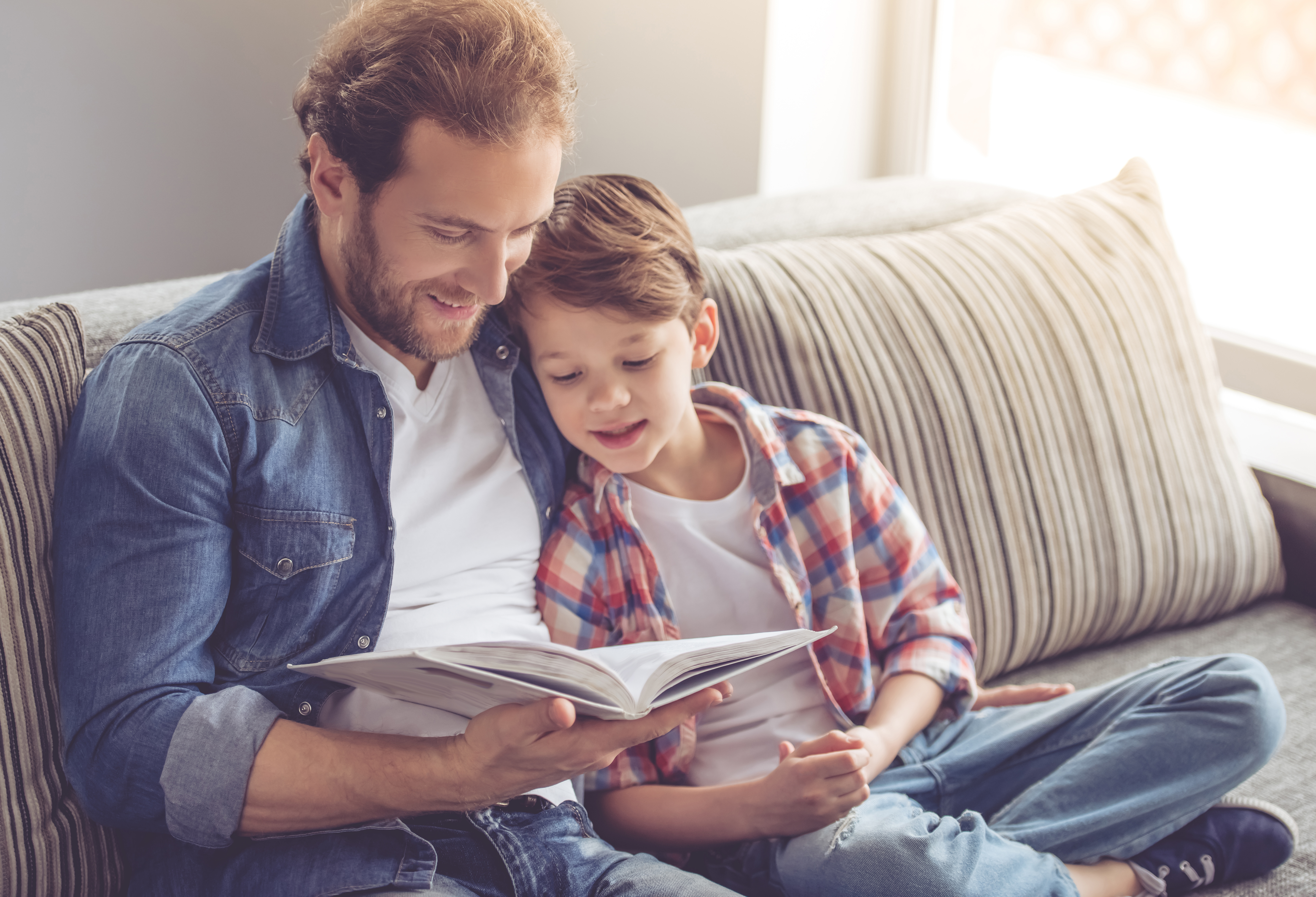 Father and son reading a book and smiling | Source: Shutterstock