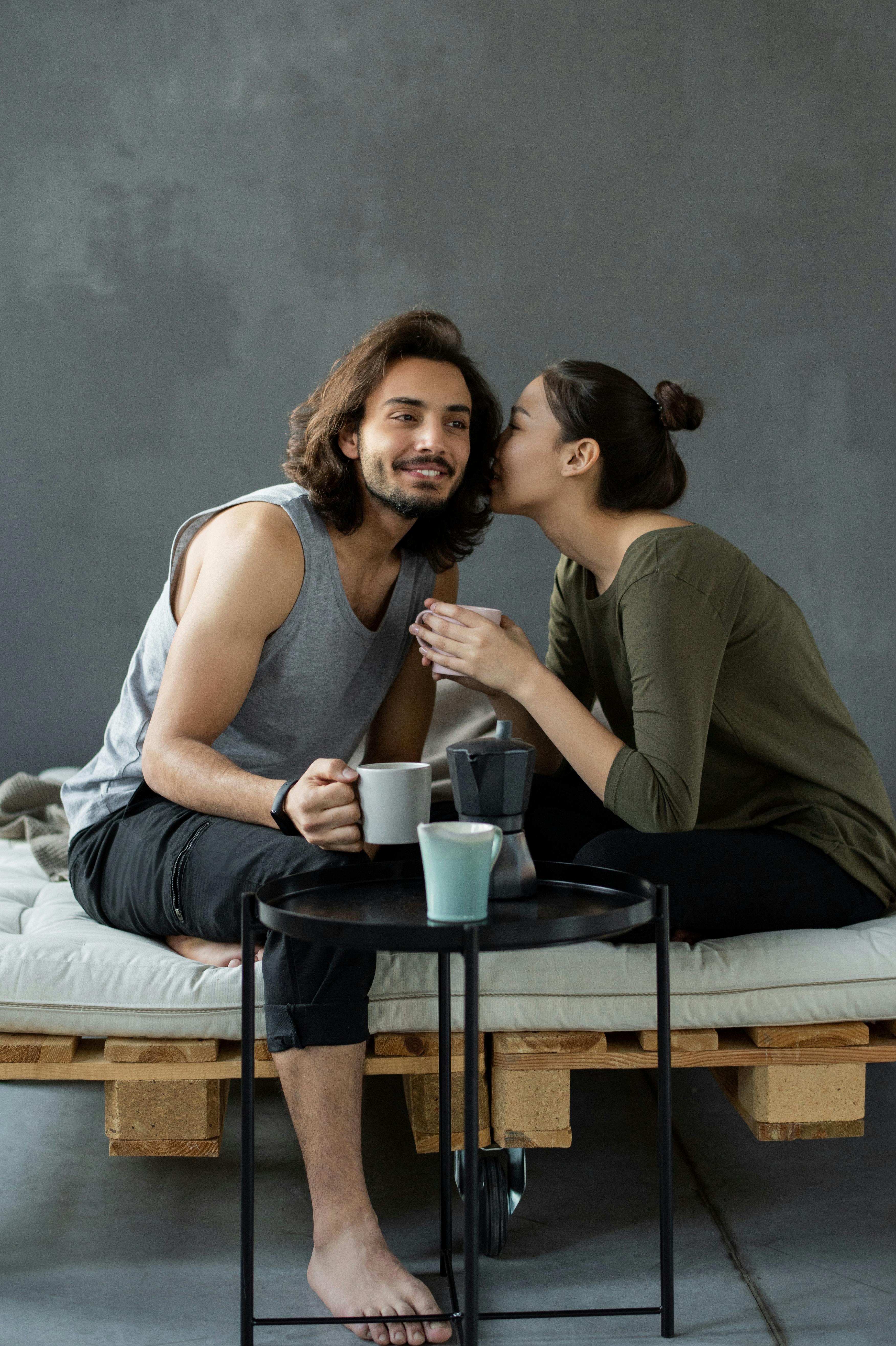 A man smiling while a woman whispers something to him while having beverages | Source: Pexels