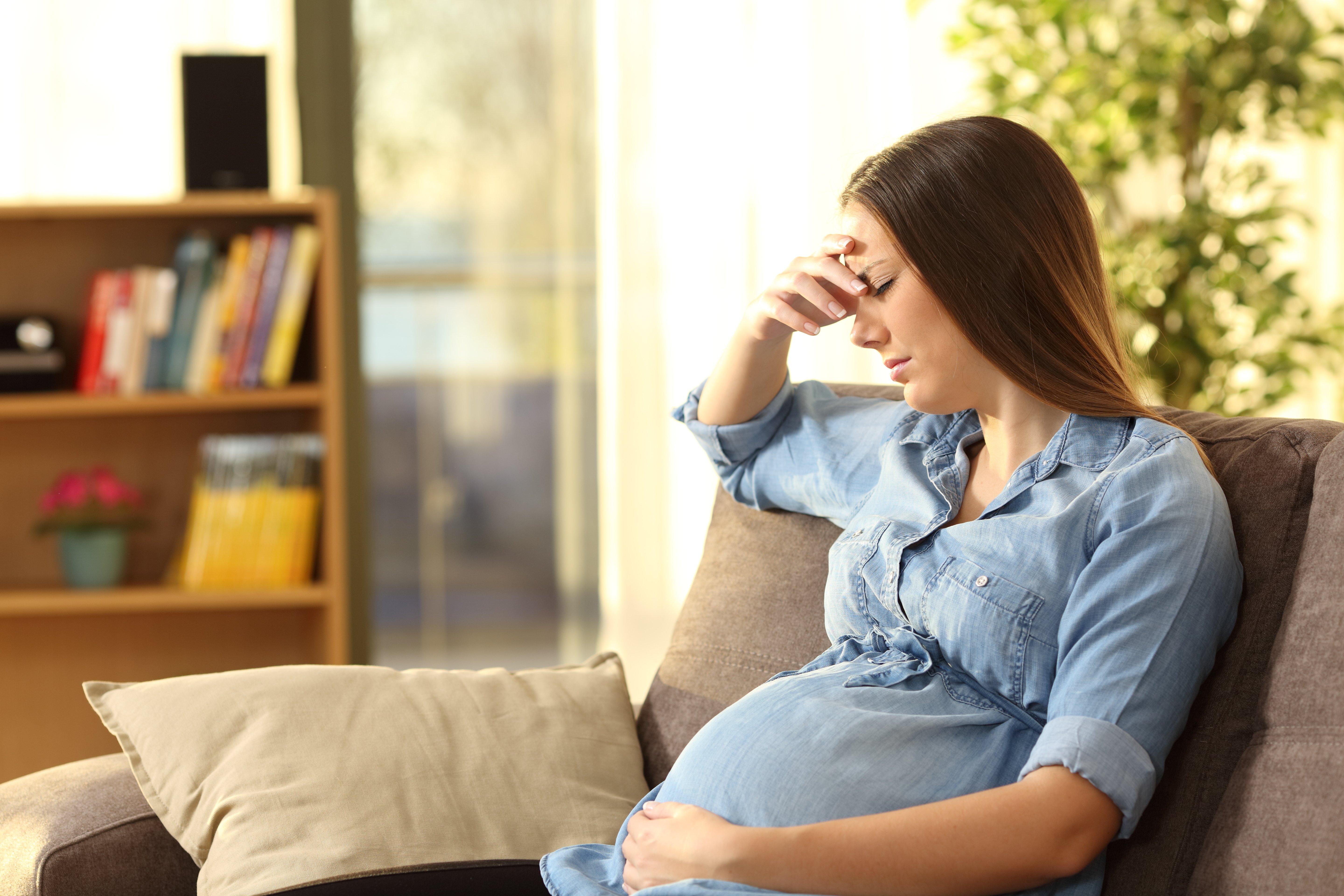 Pregnant woman sitting on a couch  | Photo: Shutterstock