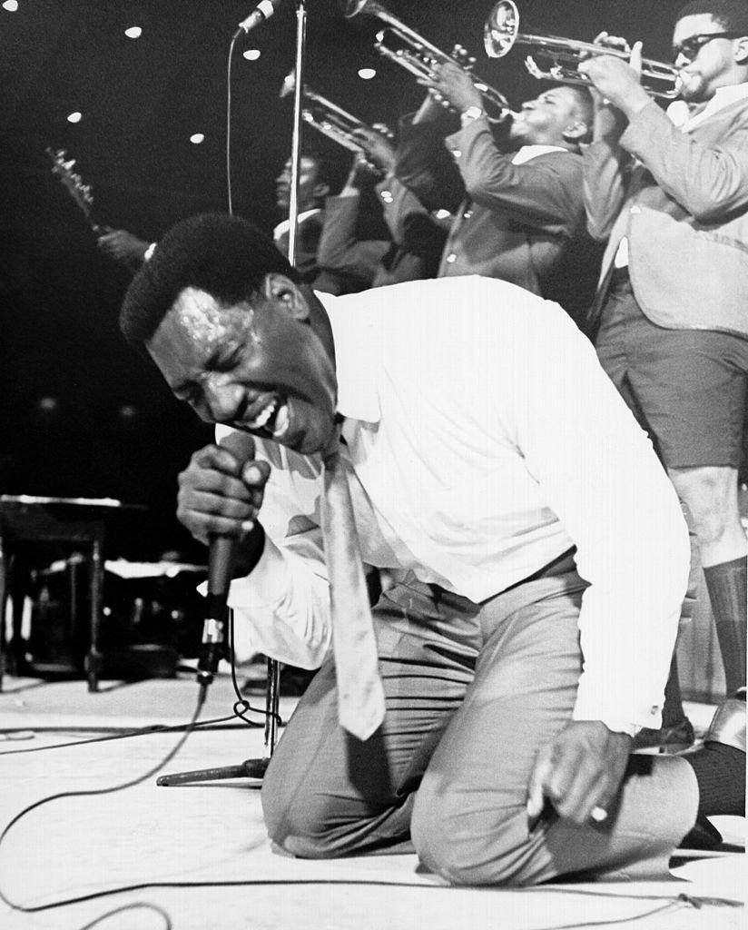 Soul singer Otis Redding passionately gets down on his knees with his horn section behind him as he performs onstage in 1967 | Photo: Getty Images