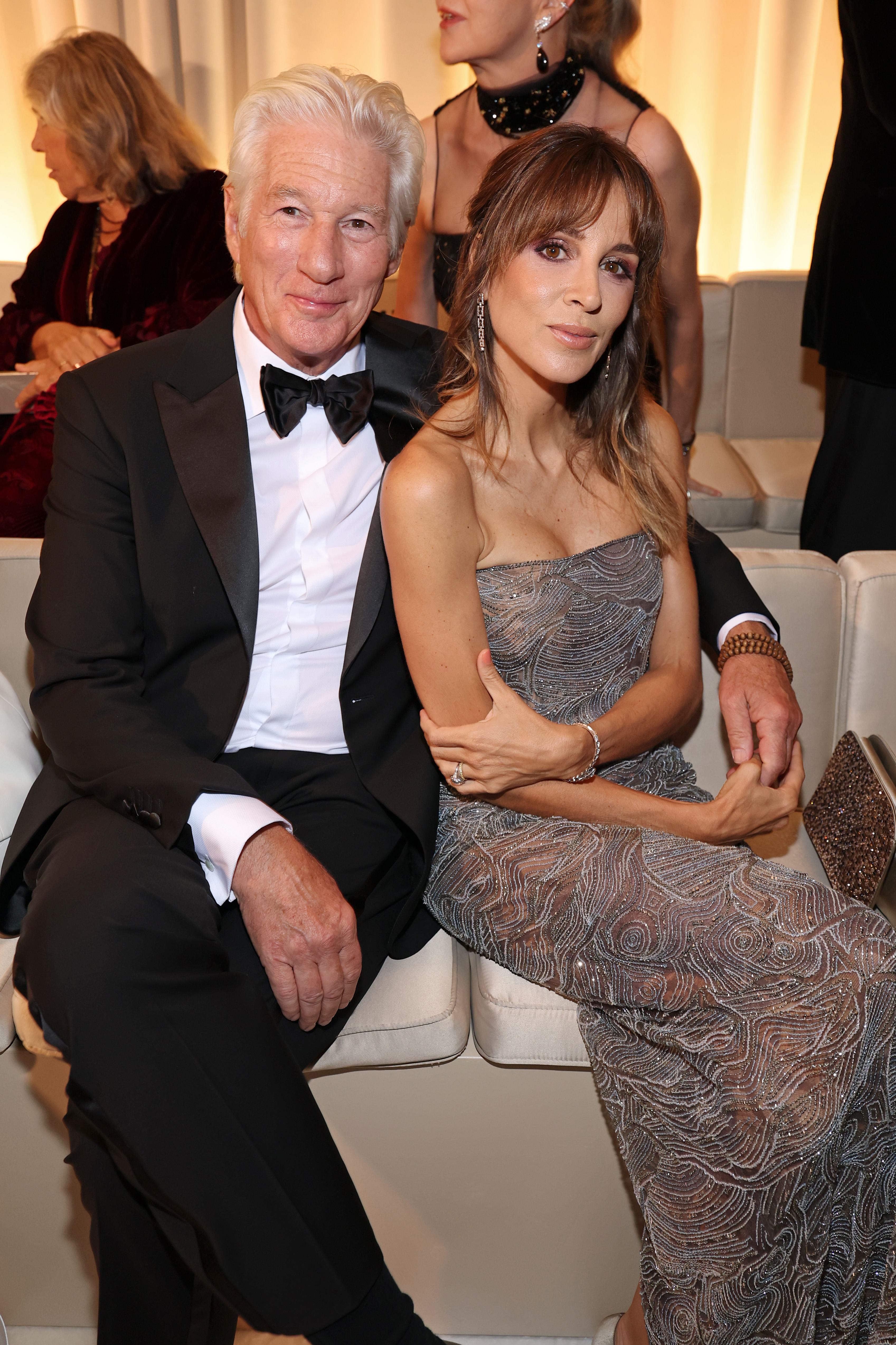 Richard Gere sits with his arm wrapped around Alejandra Silva as the couple settles into their front-row seats, both quietly confident in Armani's inner circle.