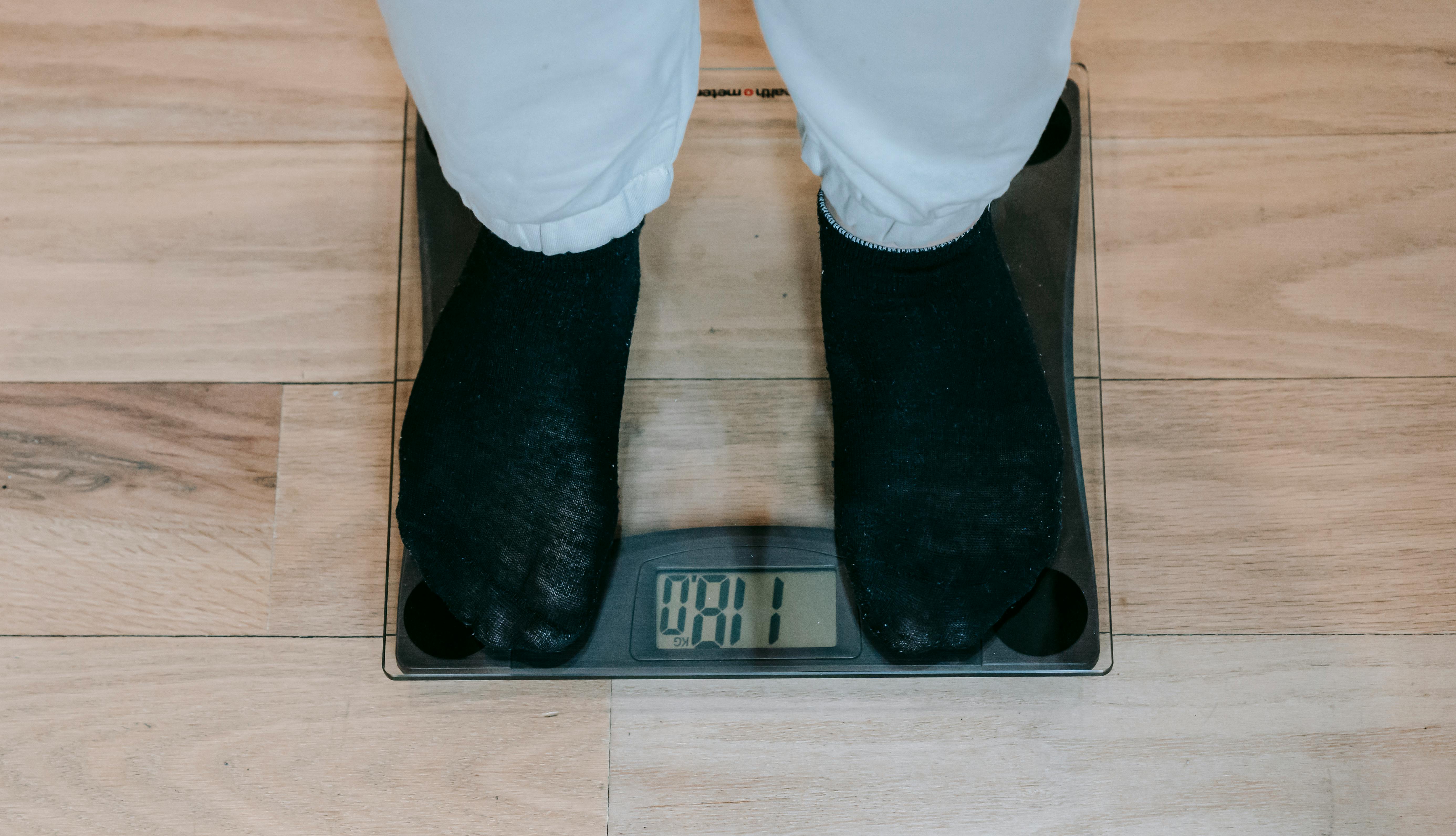 A person standing on a weighing scale | Source: Pexels