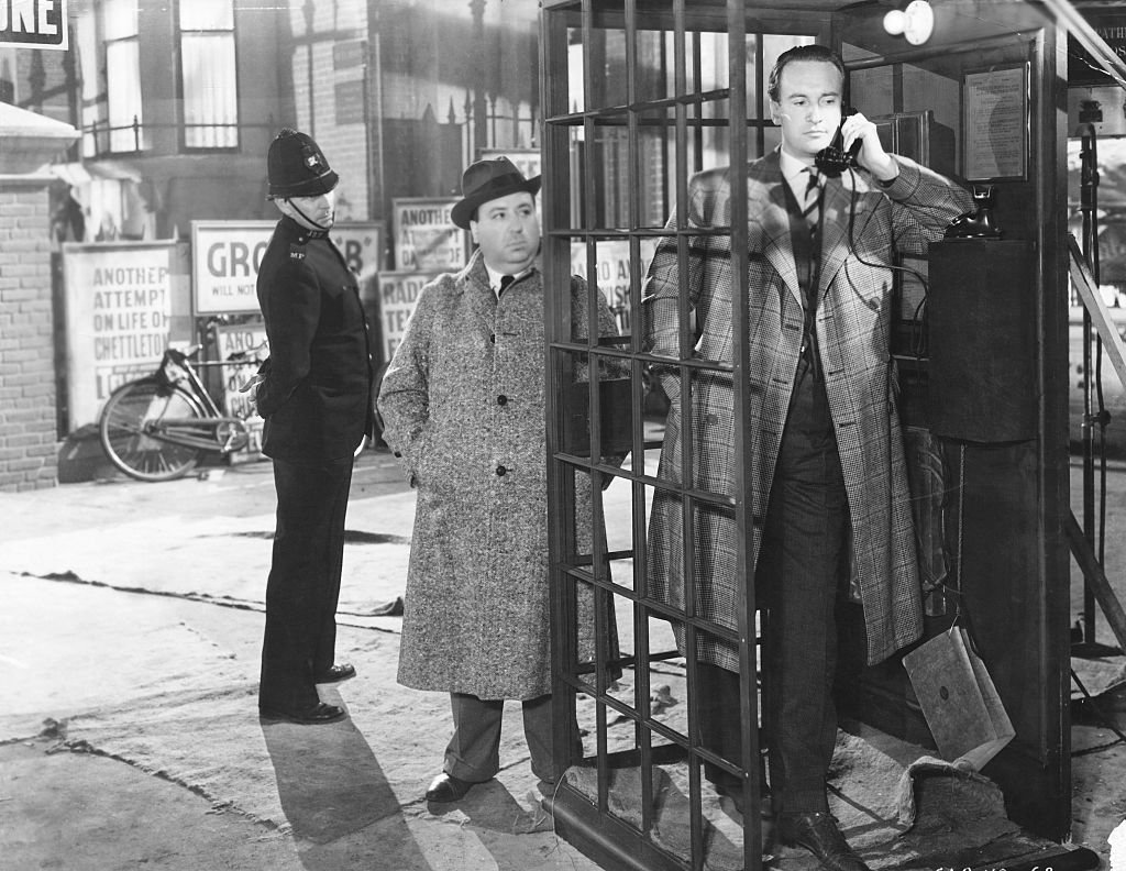 George Sanders inside a phone booth with film director Alfred Hitchcock on the side for the film "Rebecca" in January 1940. | Photo: Getty Images
