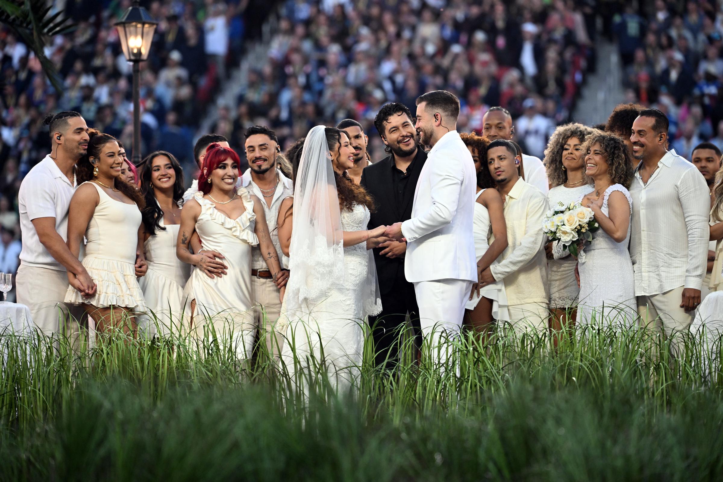 Performers portray a wedding scene during Bad Bunny's set, with dancers and cast arranged in a staged moment on the field at Levi's Stadium.