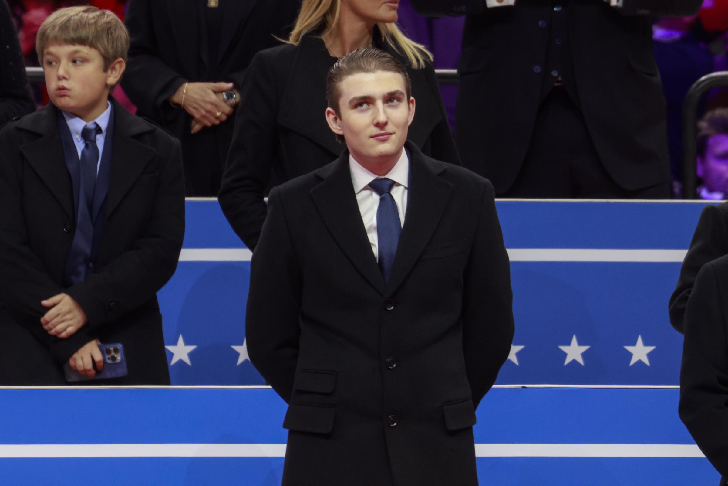 Barron Trump smiles subtly and looks on during an inauguration event. | Source: Getty Images