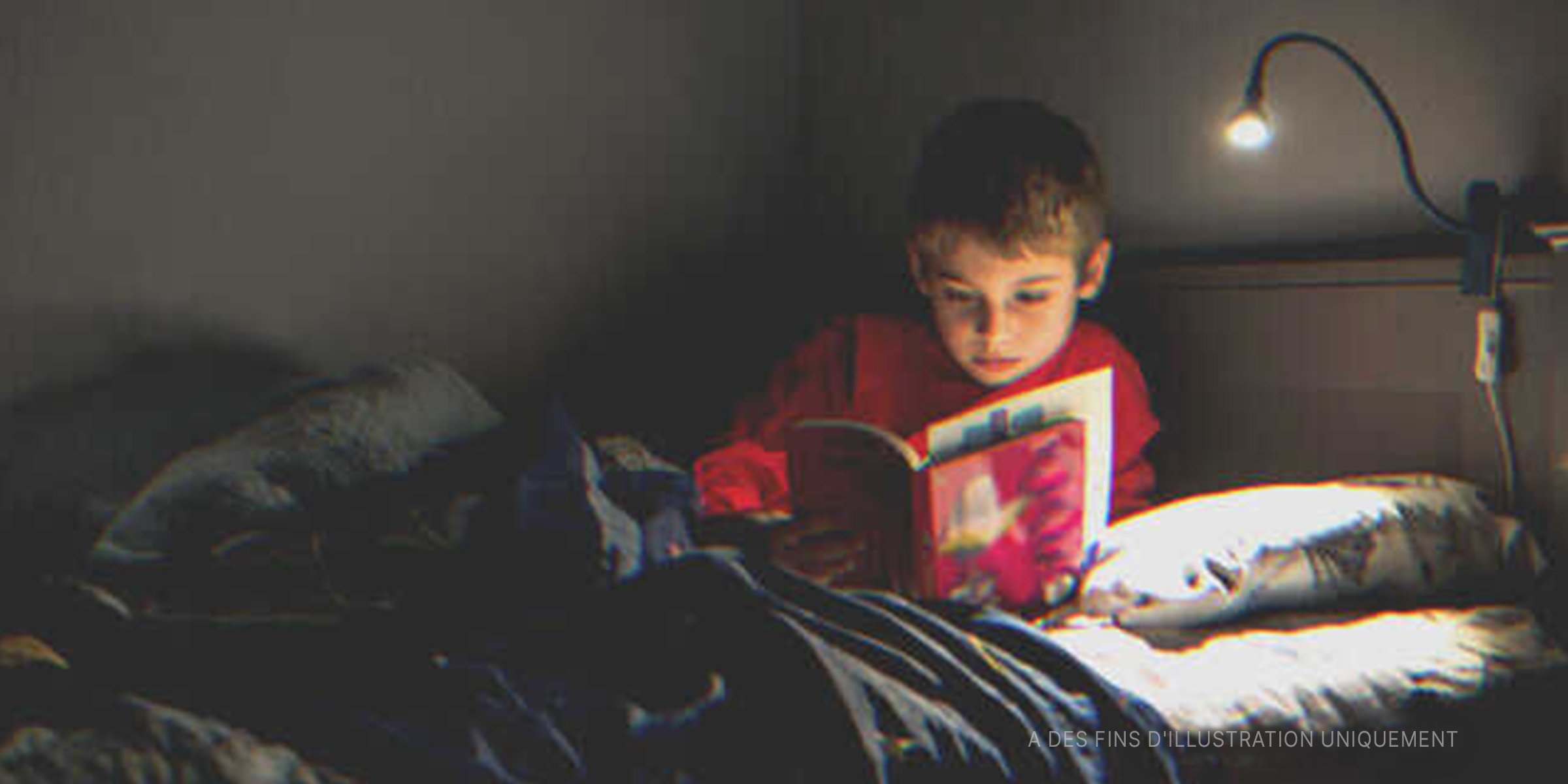 Un petit garçon en pleine lecture dans son lit | Source : Getty Images