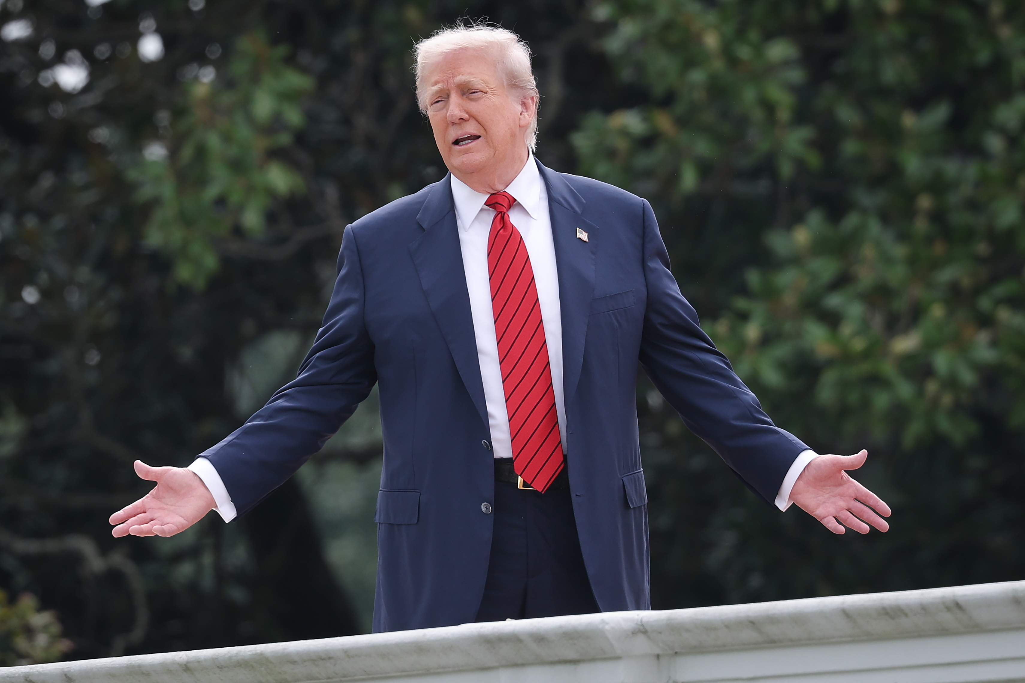 During a rare rooftop walk on the West Wing of the White House, President Donald Trump spreads his arms wide while answering reporters, making the moment a spectacle.