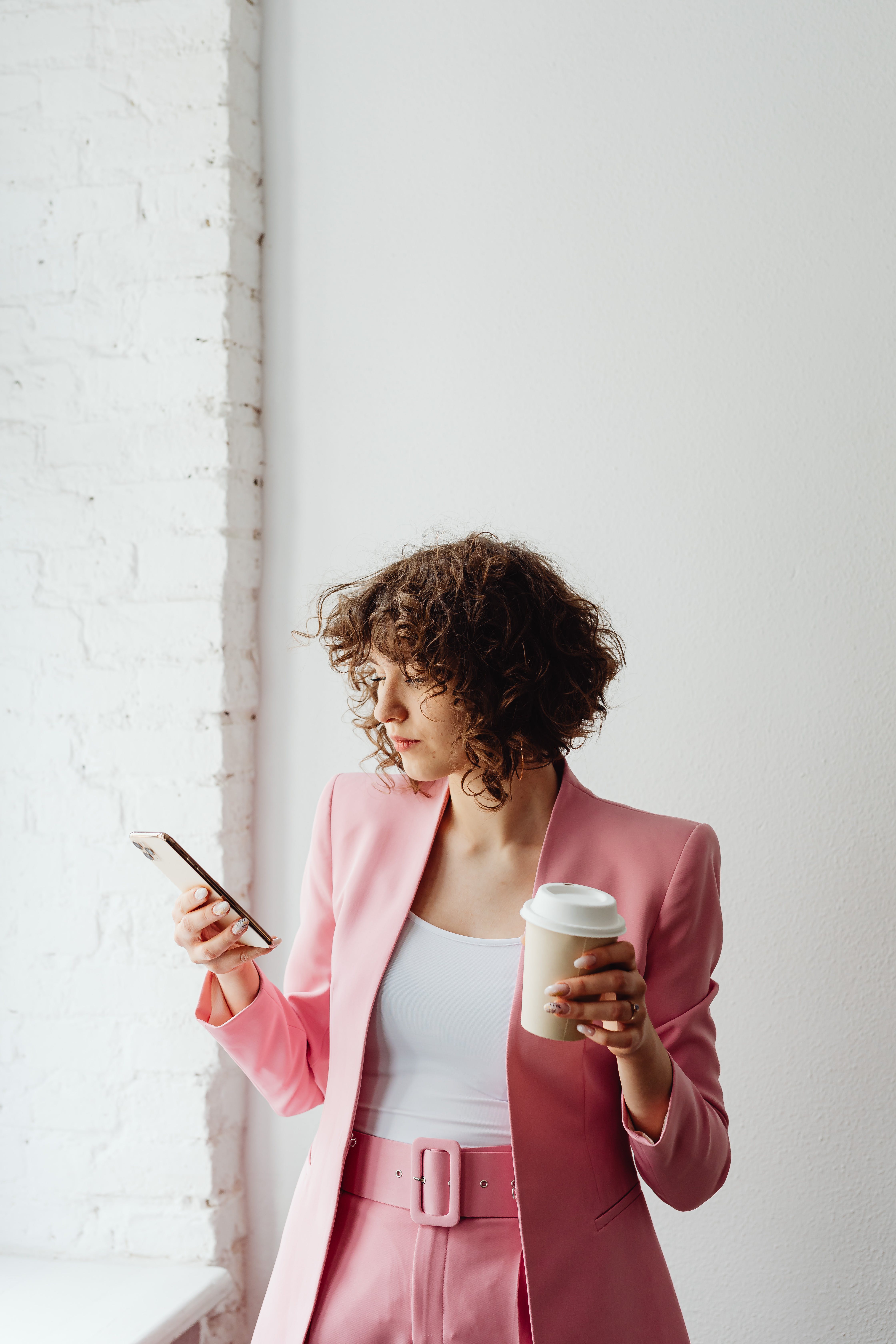 A woman holding a beverage while texting on her phone | Source: Pexels