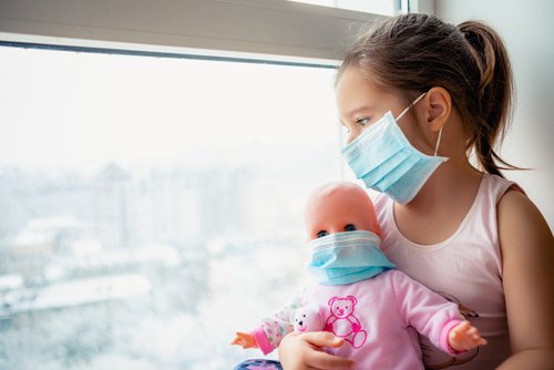 Niña con mascarilla mientras sostiene su juguete. | Foto: Shutterstock