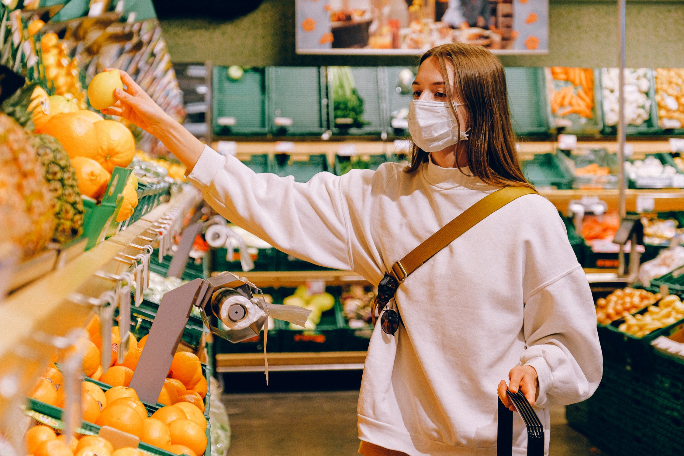 Mujer haciendo compras en supermercado mientras utiliza una mascarilla. | Foto: Pexels