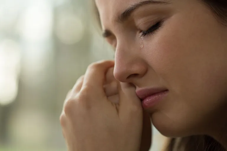 Une femme pleure en regardant par la fenêtre. | Source : Shutterstock