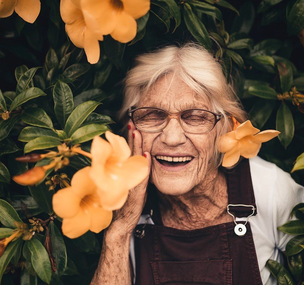 Abuelita sonriendo entre los arbustos. | Foto: Pexels