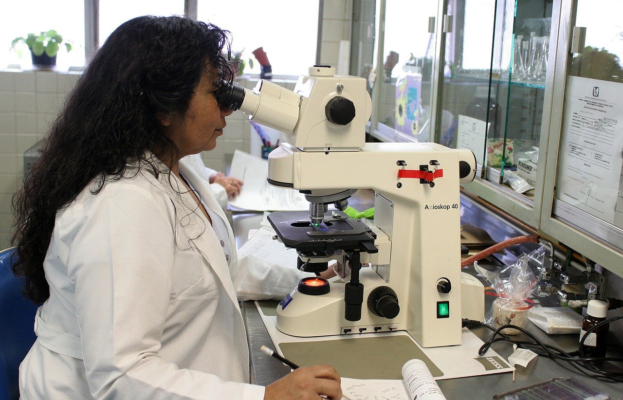 A woman looking through a microscope. | Photo: Pixabay