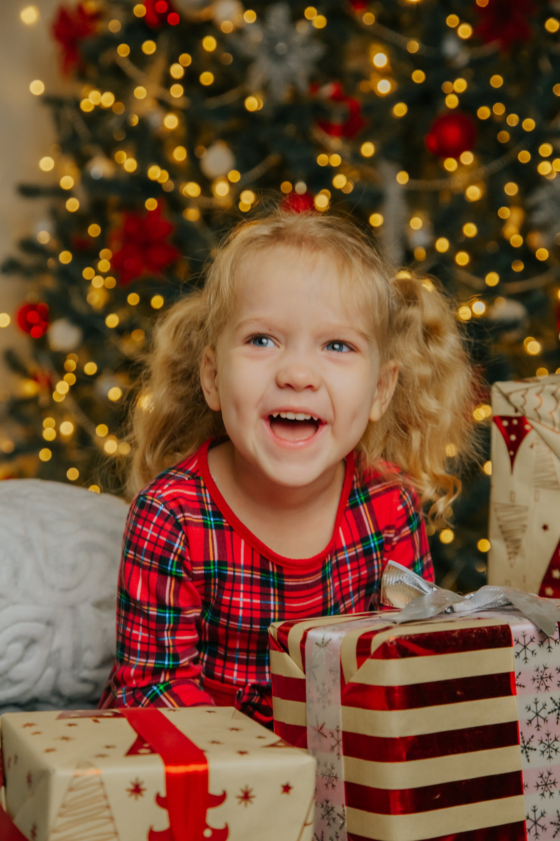 A smiling little girl holding Christmas presents | Source: Pexels