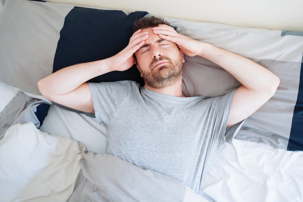 Ein Mann, der früh mit Kopfschmerzen aufwacht. I Quelle: Shutterstock