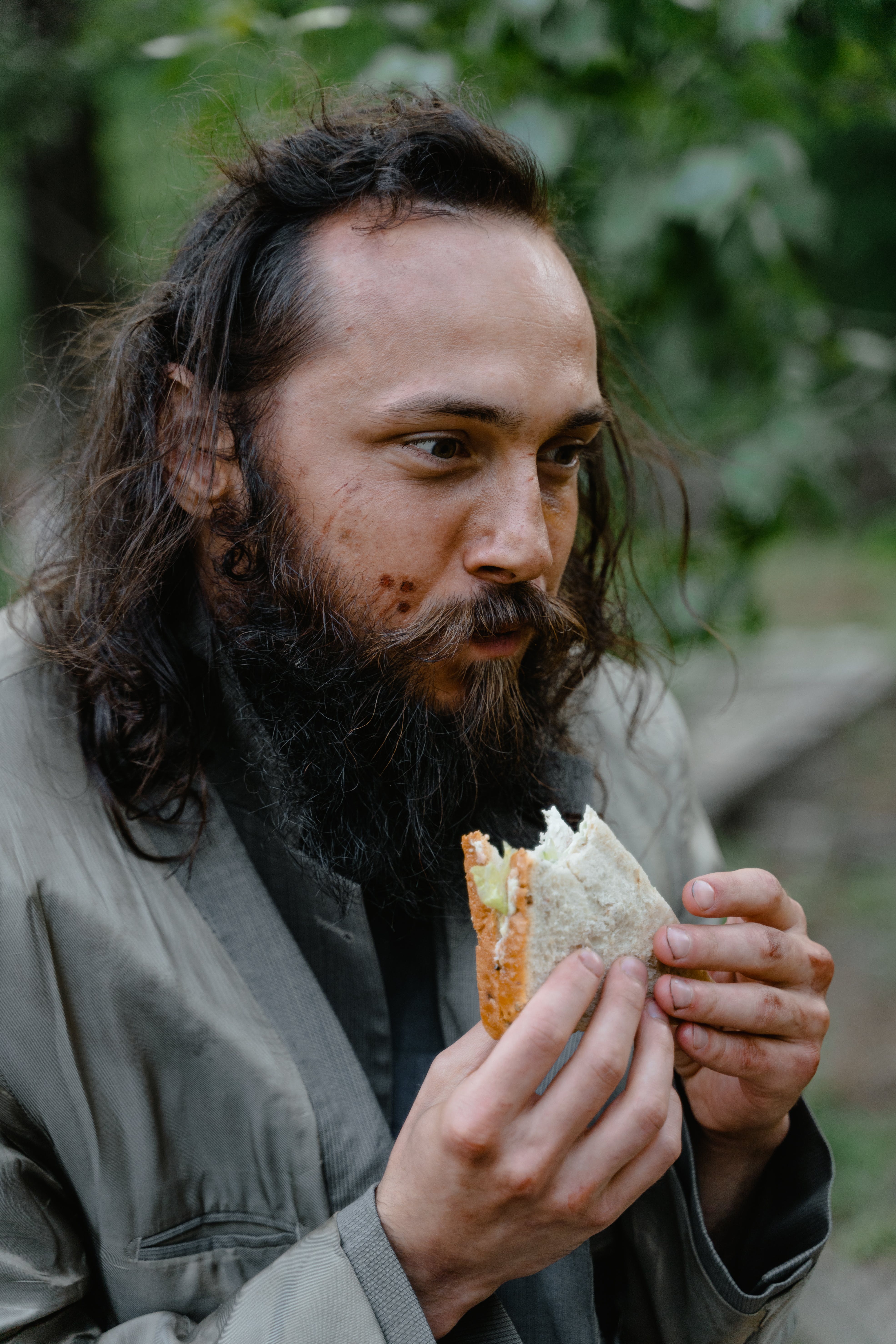 A homeless man looking happy while eating some food | Source: Pexels