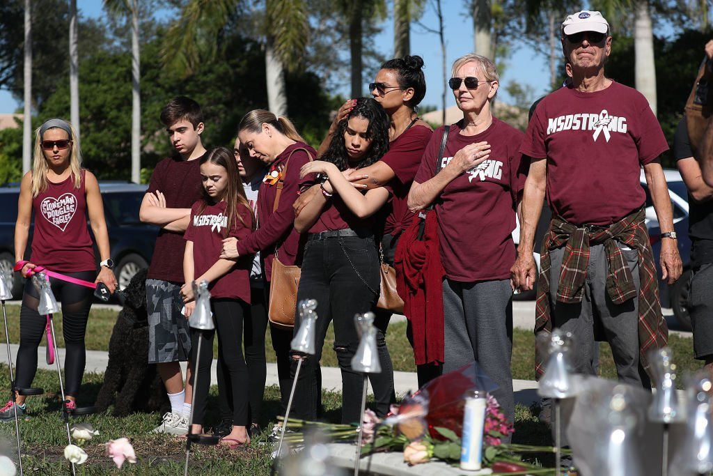 People pause for a moment of silence at 10:17 am on Thursday, February 14, 2019 near Marjory Stoneman Douglas High School as they remember those lost during the Parkland Mass Shooting. | Photo: Getty Images