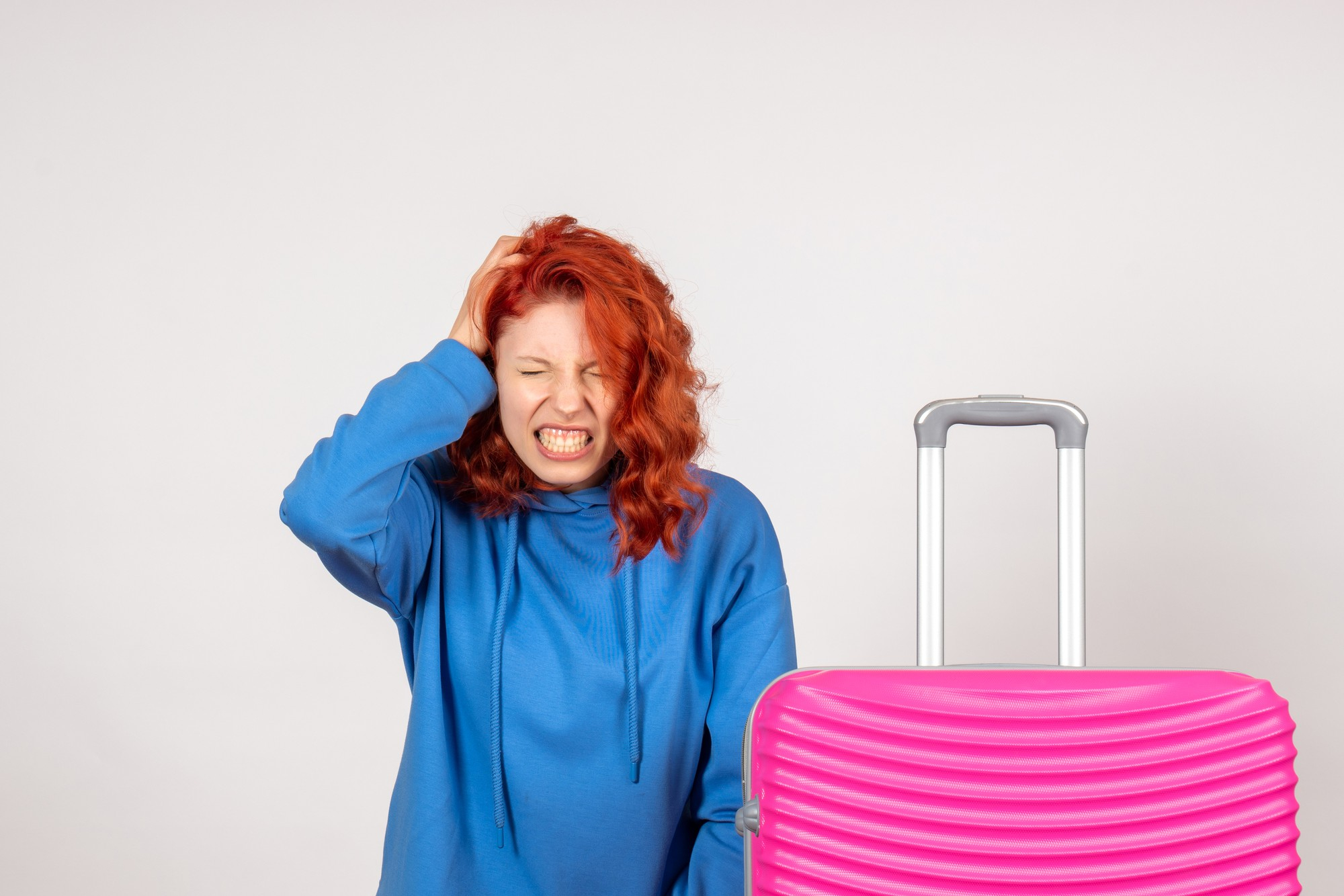An upset woman standing with her luggage | Source: Freepik