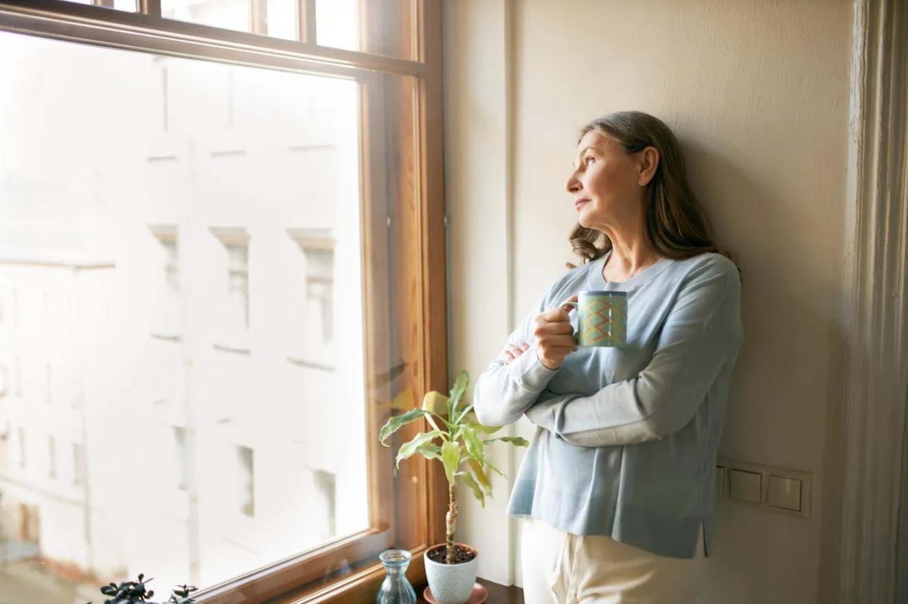 Mature woman standing near a window | Source: Freepik