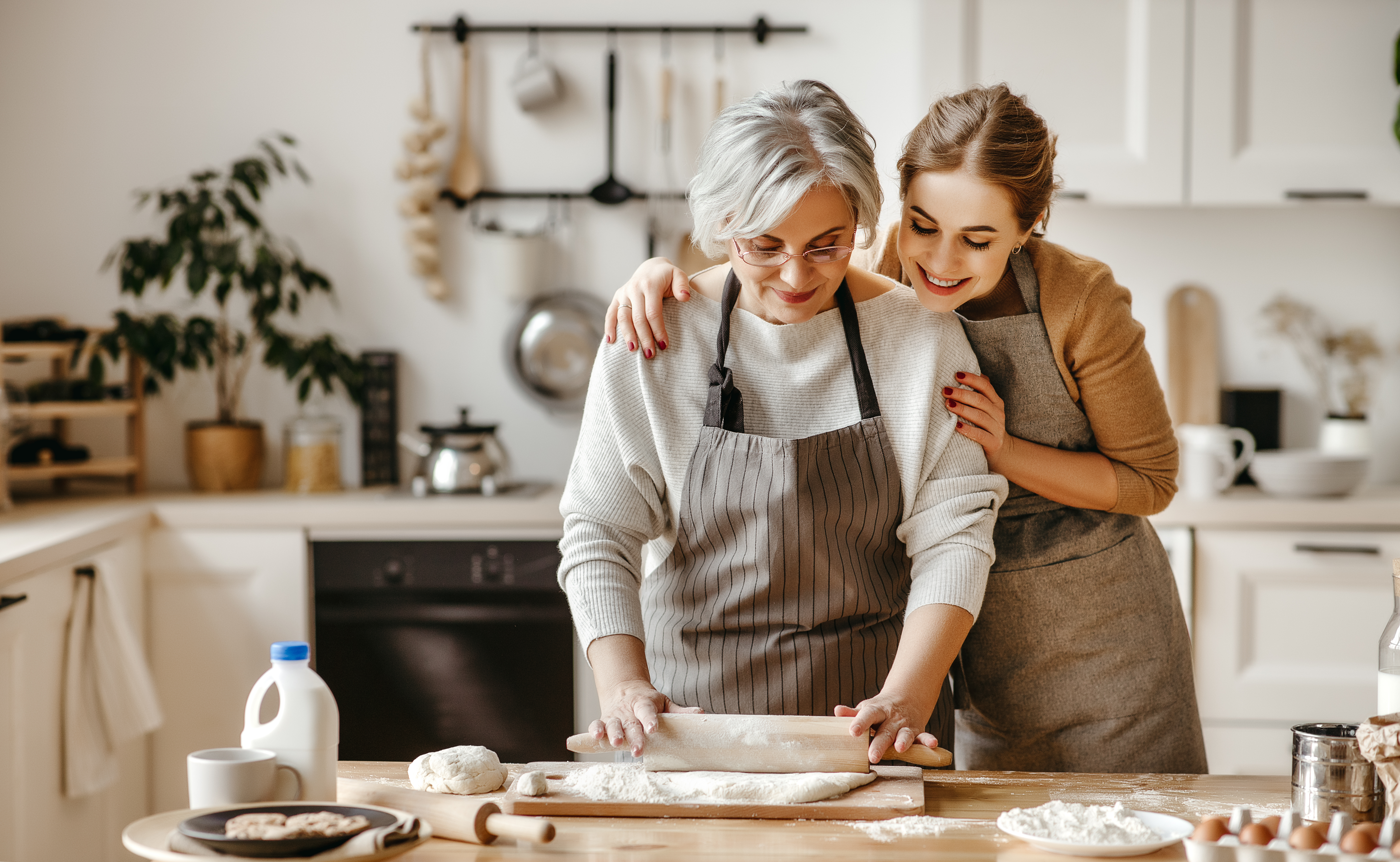A woman lovingly embracing her mother-in-law while they bond over baking | Source: Shutterstock